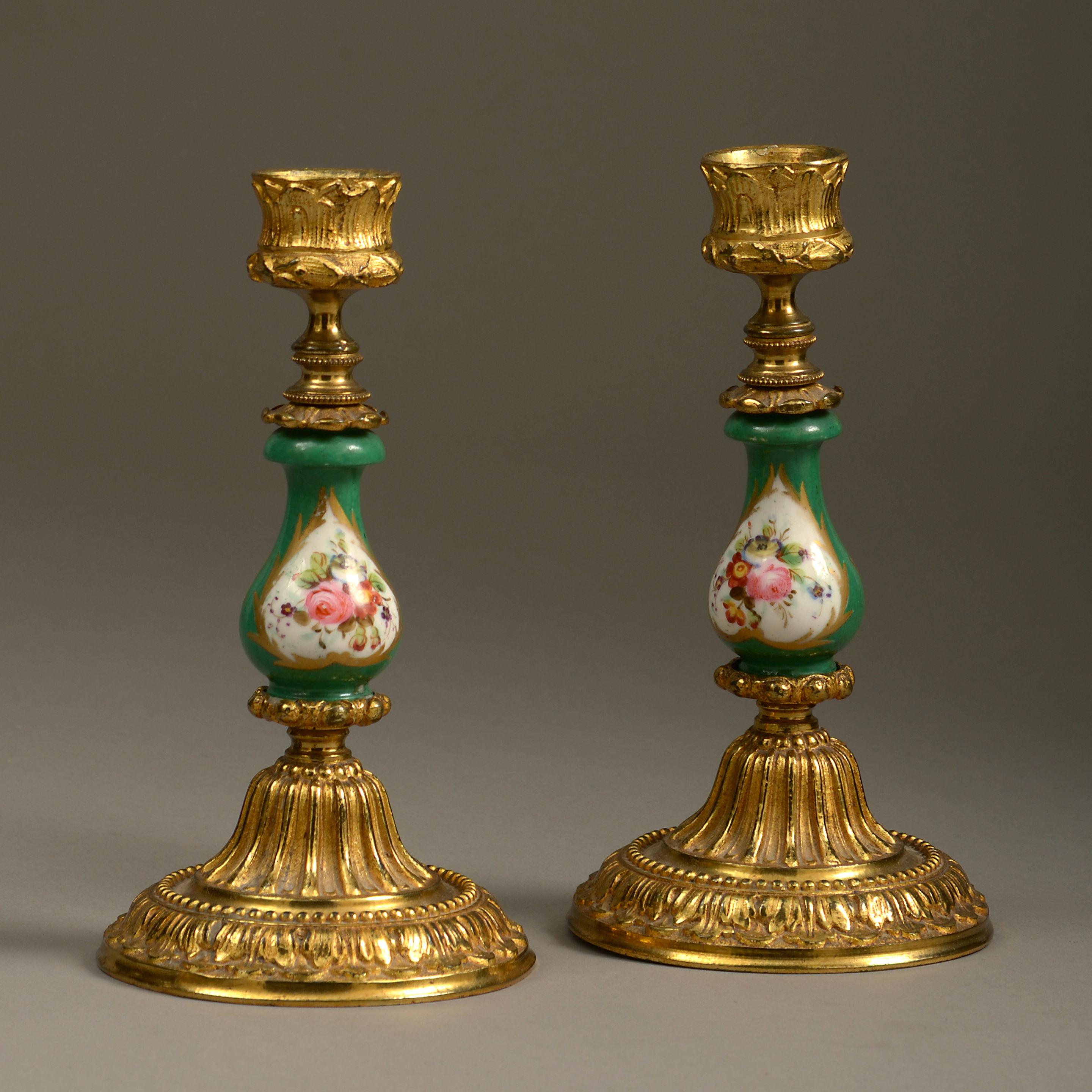 Ein Paar Kerzenständer aus der Mitte des 19. Jahrhunderts mit Sockeln und Sockeln aus Ormolu im Stil Ludwigs XVI., die Stiele aus Sèvres-Porzellan mit Blumenkartuschen auf grünem Grund im Stil des Rokoko.