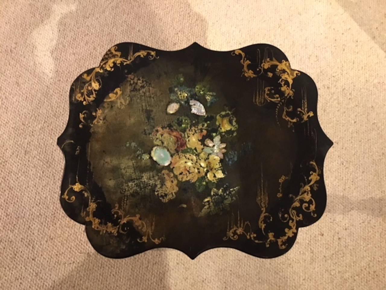 A 19th century papier mâché and ebonized shaped wine table. Having a shaped papier mâché top with gilded, painted and mother-of-pearl floral detail, supported on an ebonized and gilded column with three umbrella shaped supports, English, circa