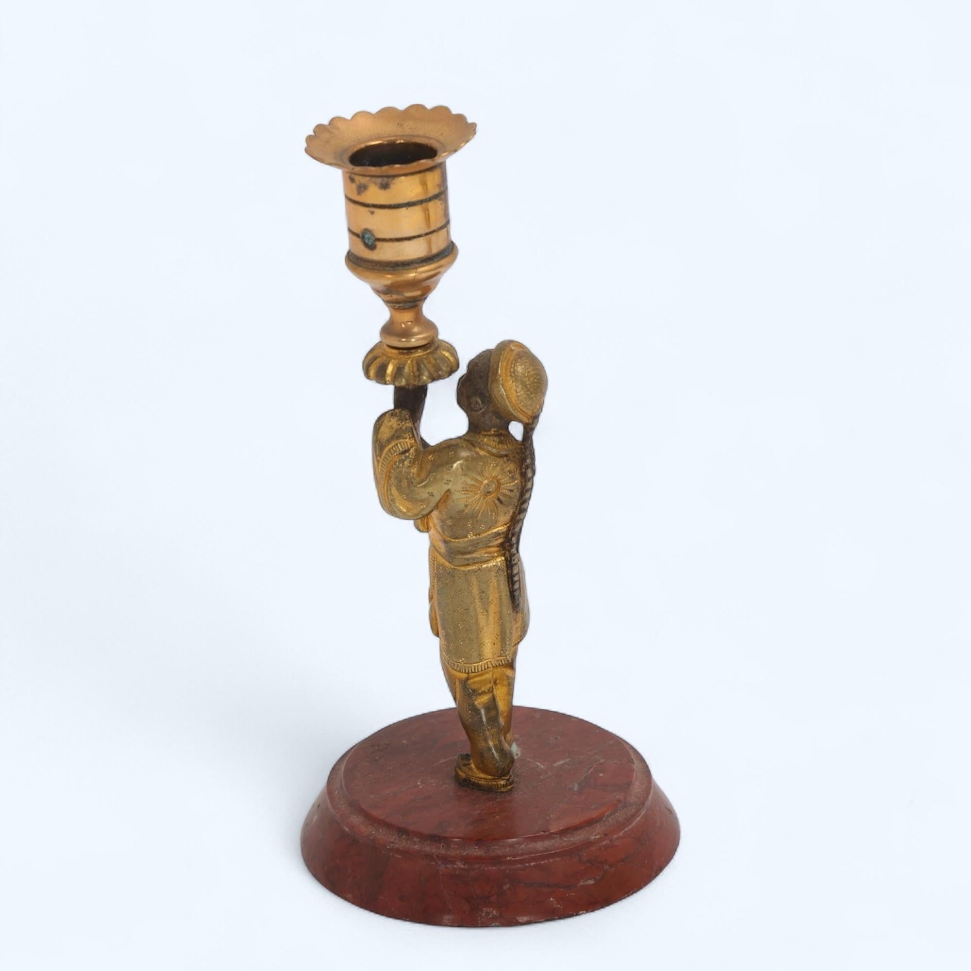 19th Century Parcel-Gilt Bronze Candlestick on Rouge Marble Base

This charming 19th-century gilt-bronze candlestick features a Chinese figure dressed in traditional gown with intricate detailing, holding a torch that forms the candle socket holder.