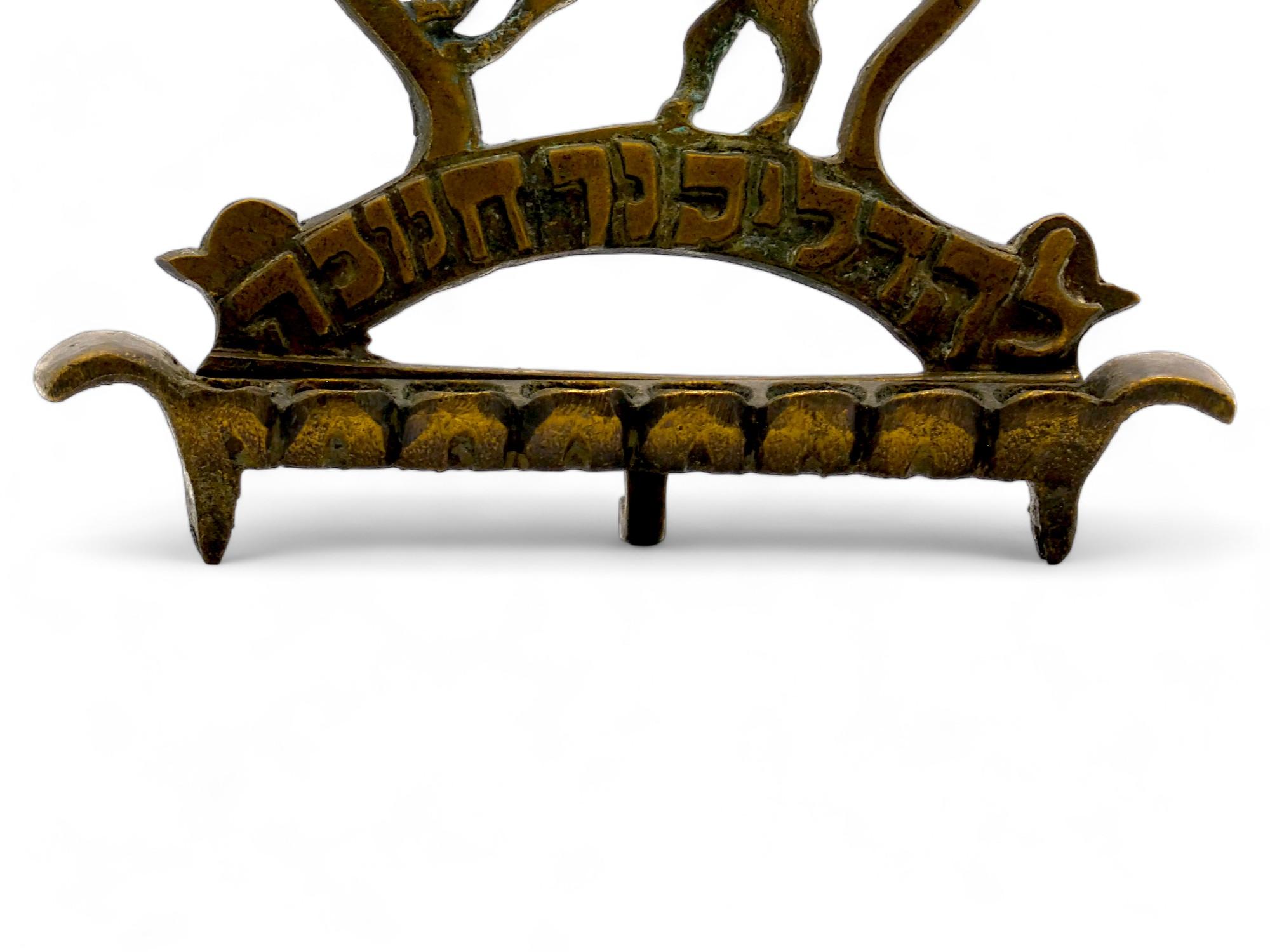 Lampada Hanukkah in ottone polacco del XIX secolo.

La piastra posteriore in fusione presenta un leone trafitto appoggiato su un lato di una corona maestosa.

