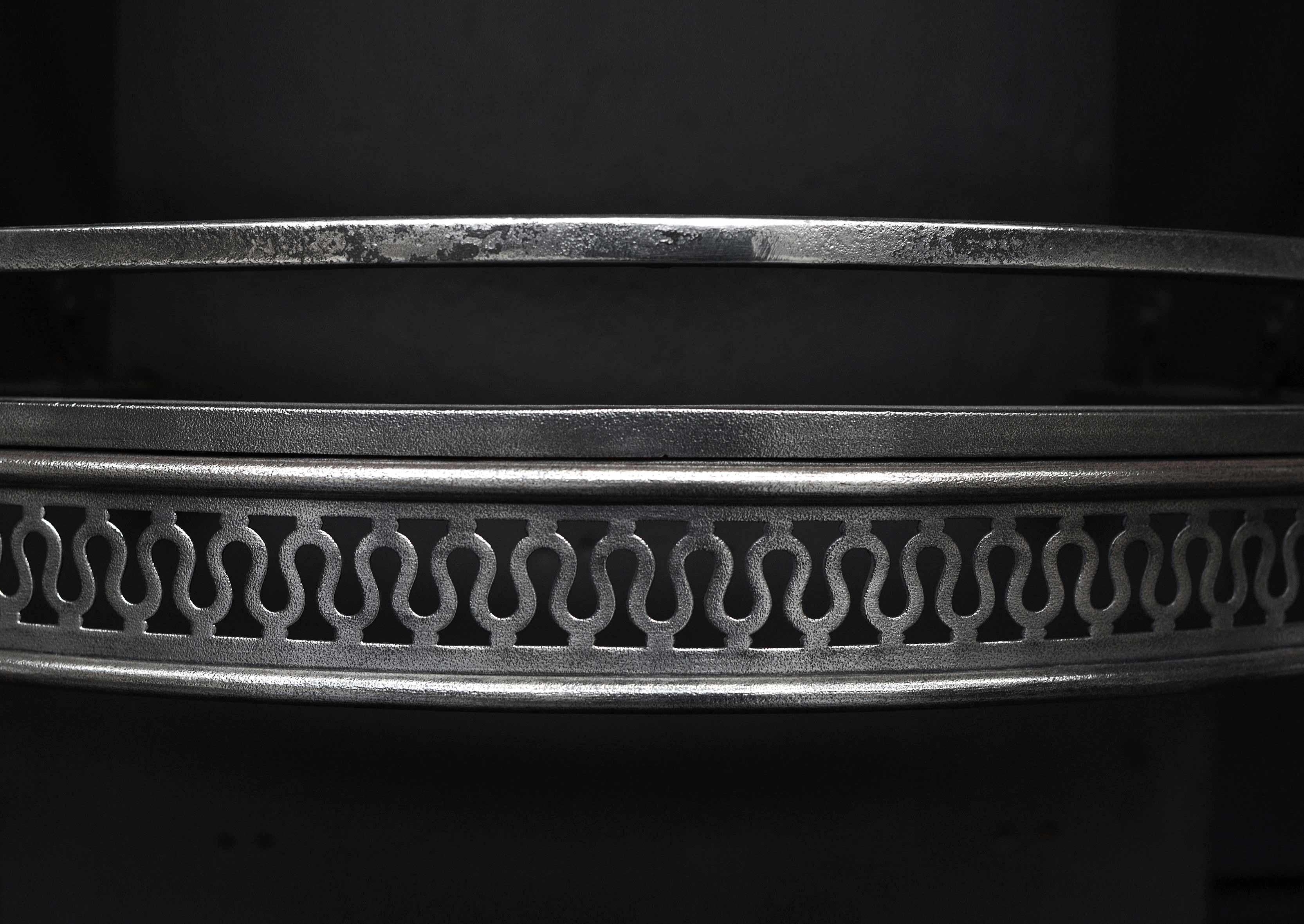 A 19th century polished steel firegrate. The shaped feet surmounted by urn finial, with interlocking guilloche fret work. Shaped burning area above. Shaped cast iron back behind.

Measures: Width at front: 840 mm 33 ?