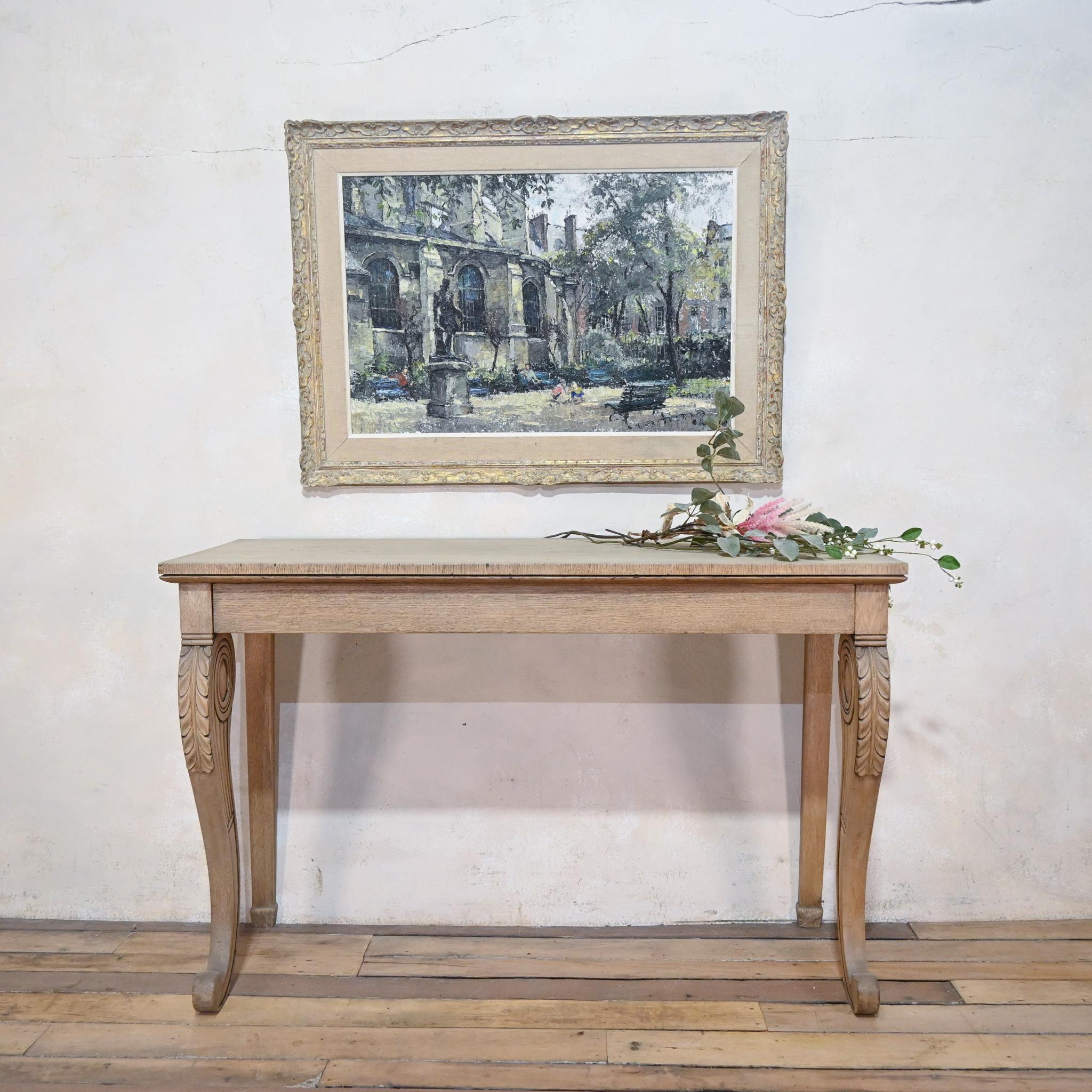 An elegant bleached oak regency console table. Displaying a pair of elaborate scroll front legs, boldly carved with acanthus leaves. Fitted with a hidden full-length drawer. 
 
Measures: Height - 89cm 
Width - 138cm 
Depth - 51cm.

 