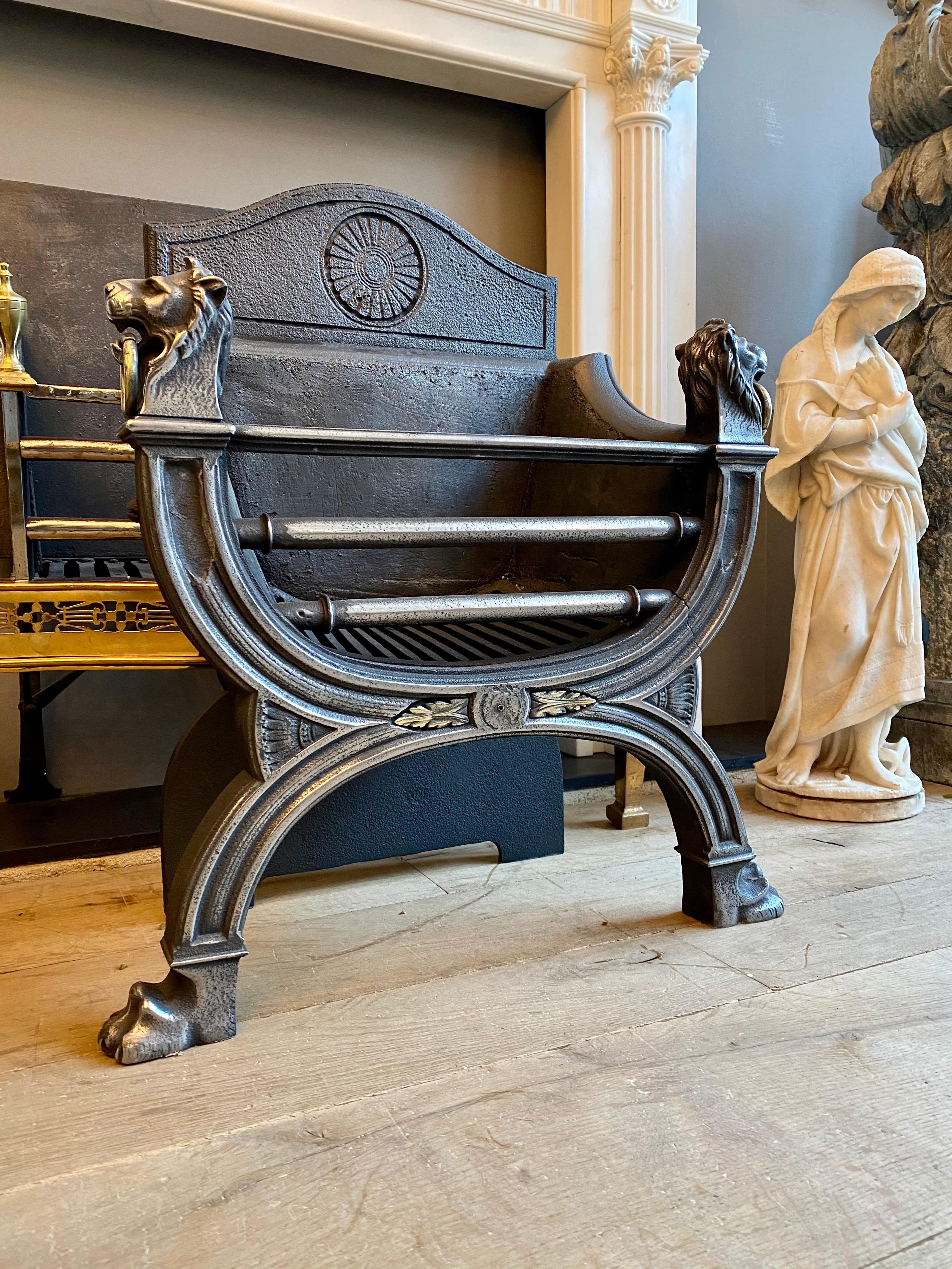An elegant and good quality English 19th century regency style fire grate in polished cast iron. The lion heads finials with brass rings in the mouths surmount a curved reeded front which is supported with lions paw feet. The shaped fire back with
