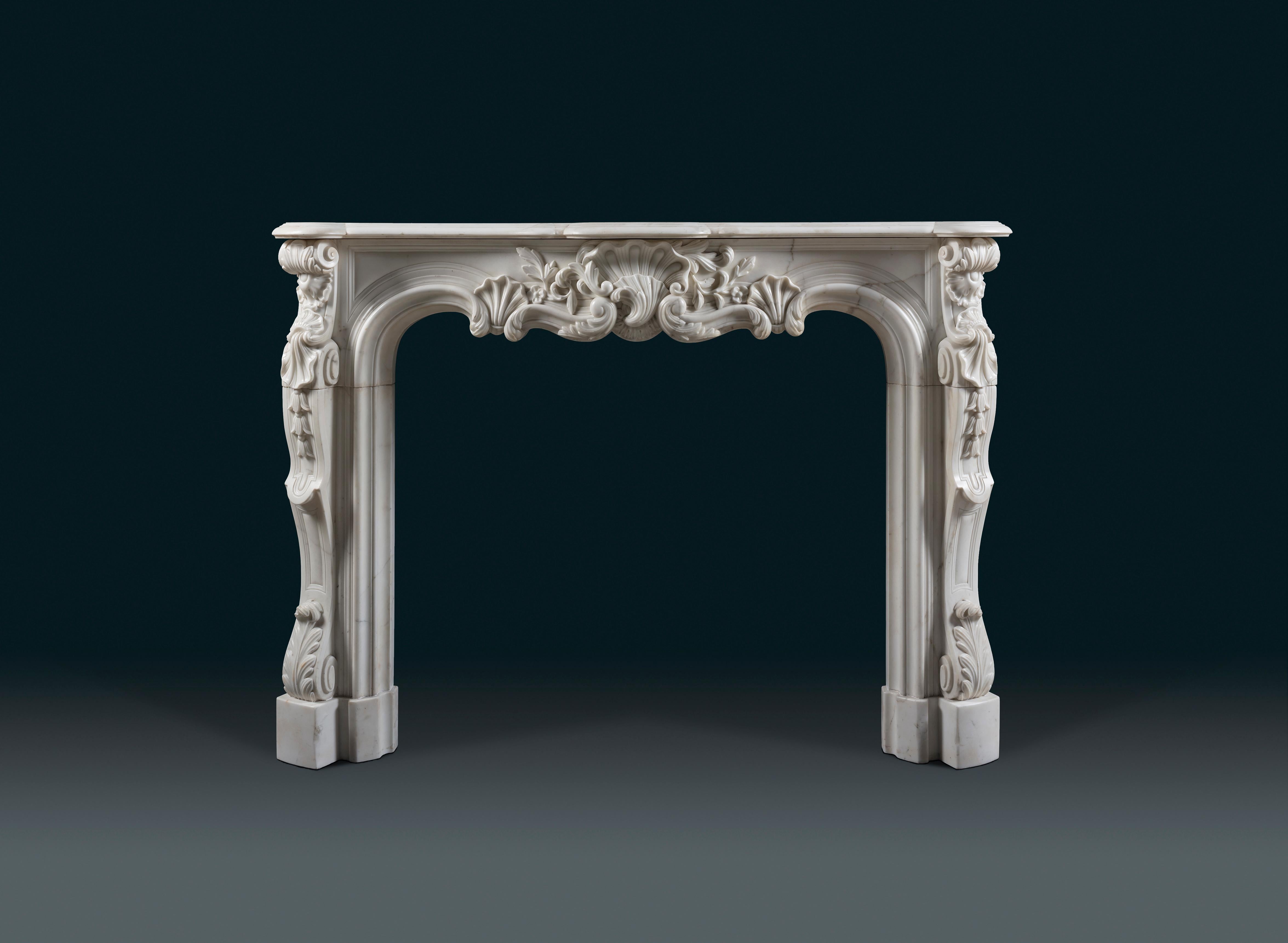 An elaborate 19th century Rococo chimneypiece in Louis XV style with an elegant, moulded shelf. The fine asymmetric serpentine frieze presents a central cartouche in the shape of a stylised shell, flanked by foliage and panels. Shell corner-blocks