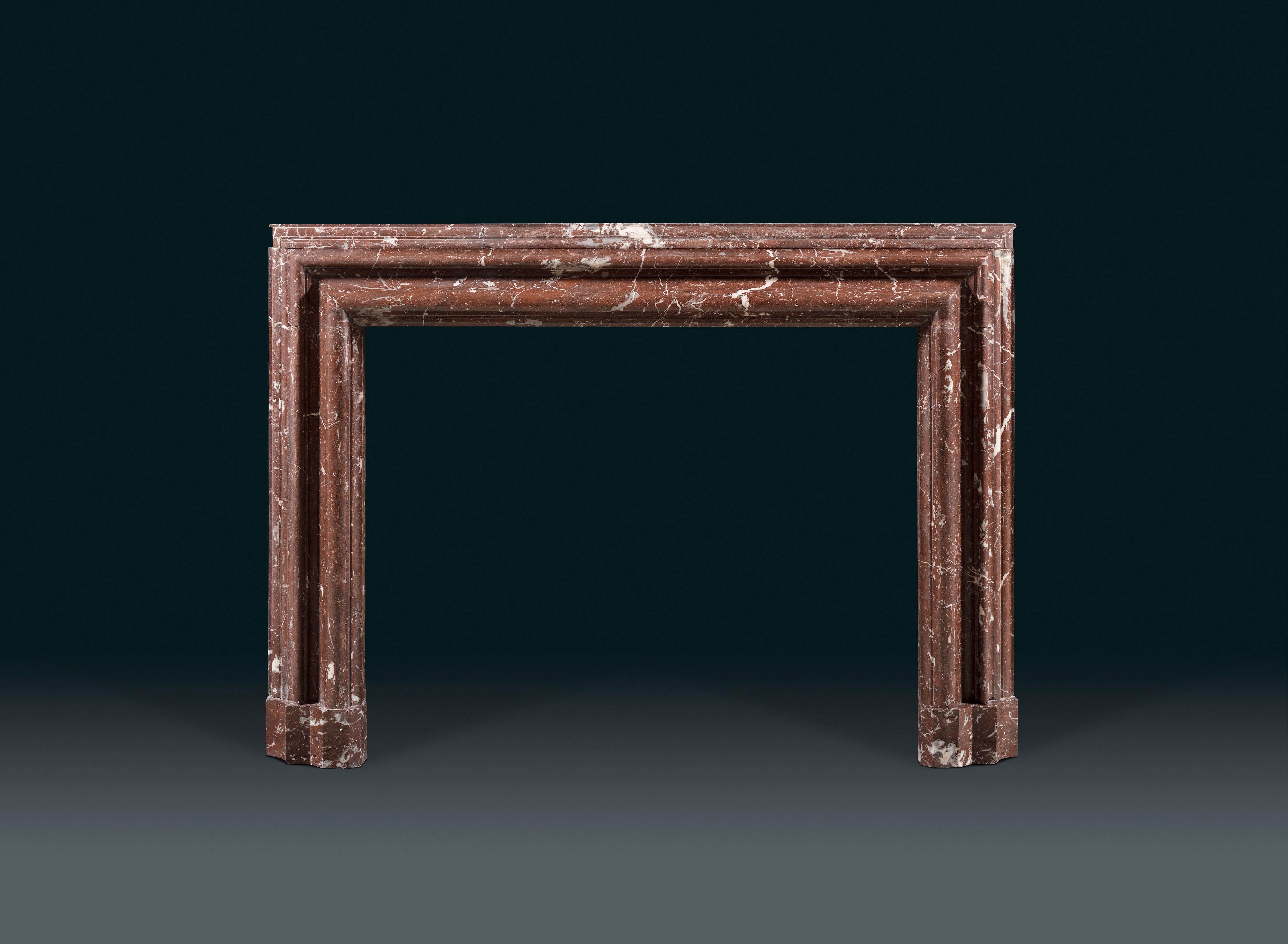 A 19th century rouge Languedoc marble bolection chimneypiece of landscape proportion on chamfered foot blocks.