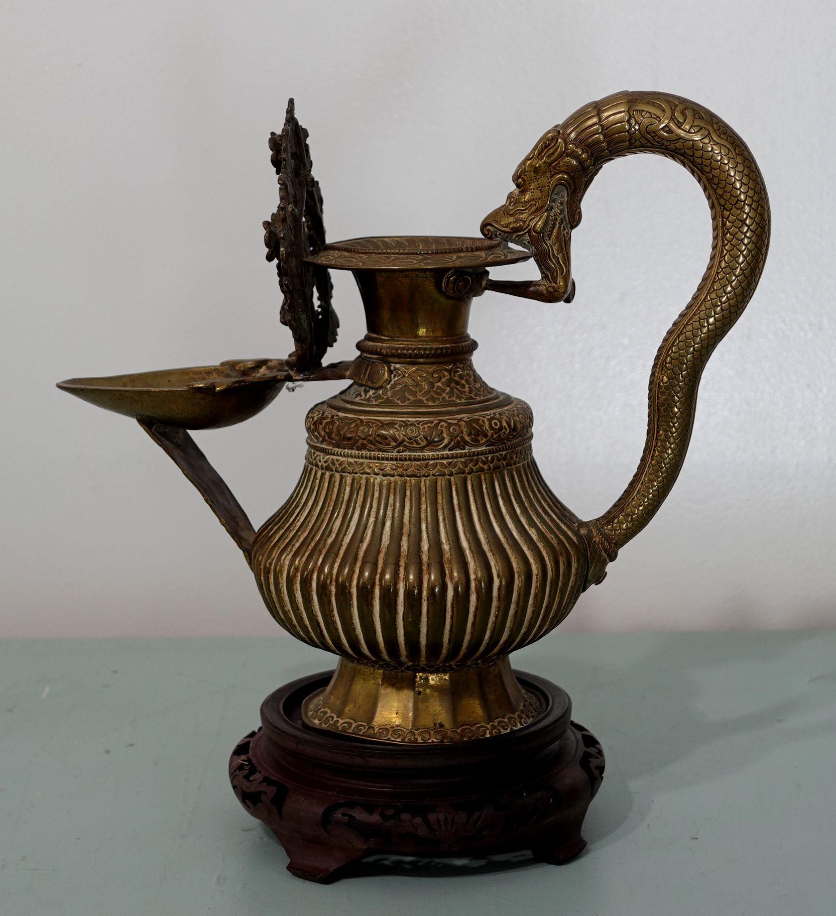 A 19th-century bronze oil lamp with intricated and complicated handcraft and carving, possibly from Tibet. The nozzle and handle feature Buddhist figures. Dimensions are 9.5 inches tall X 11.5