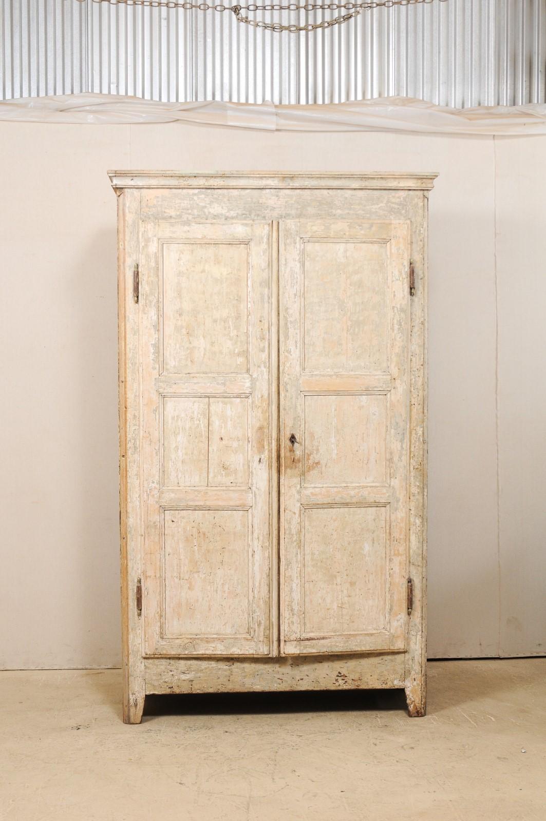 A French painted wood armoire storage cabinet from the early 19th century. This tall antique cabinet from the South of France features a molded cornice, a pair of three-panel doors which opens to reveal shelving for plentiful storage within, and is
