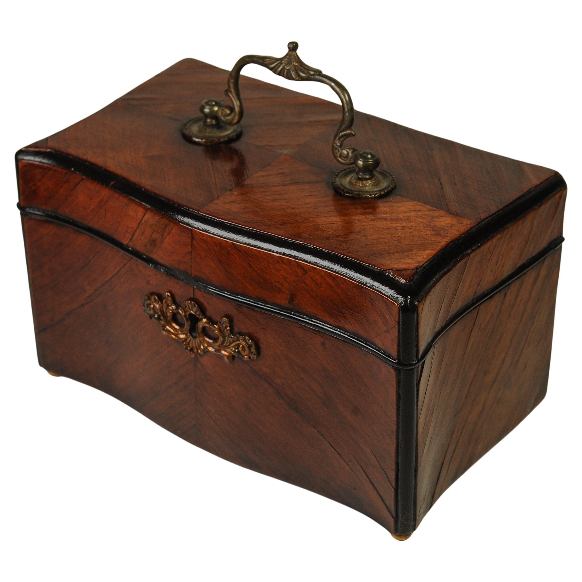 Caja de té inglesa victoriana del siglo XIX chapada en nogal ebonizado con asa de latón y forro de plomo 

Una encantadora caja para el té con parquet decorativo de chapa de nogal. 

Una caja de té es una caja, jarra, bote u otro recipiente
