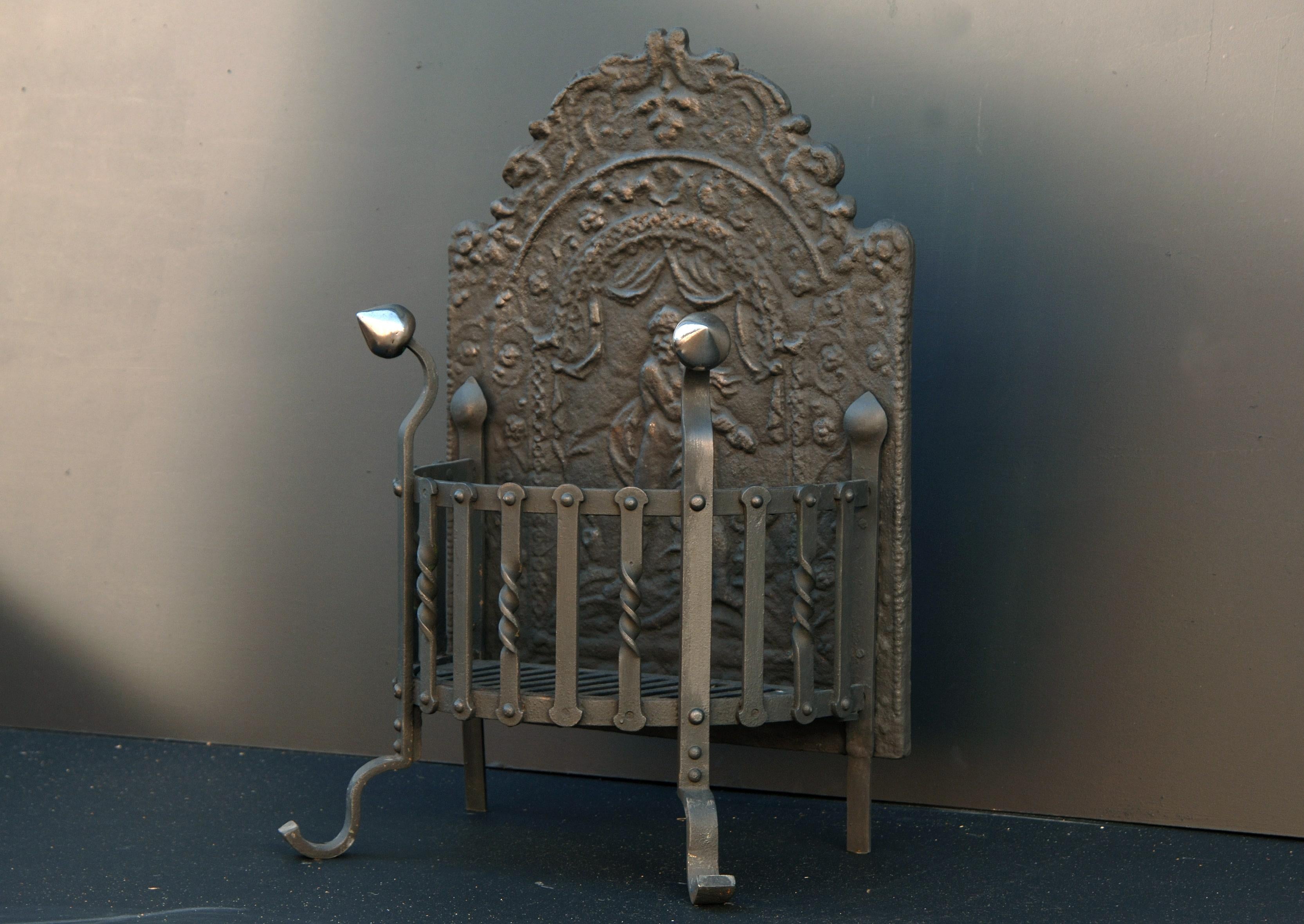 A late 19th century polished wrought iron firegrate with decorative cast fireback. Shaped burning area with finials above.

Width At Front:	455 mm      	17 ⅞