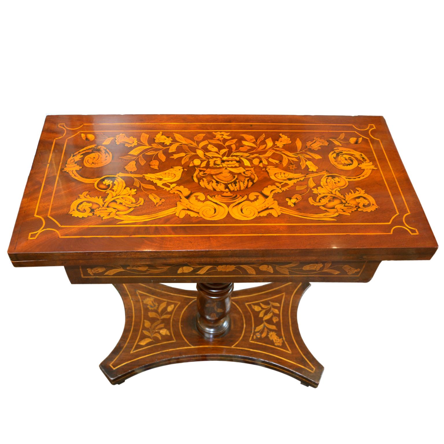 A beautifully inlaid mahogany games table, the swivel top opens to reveal a round baize lined gaming surface with the four mahogany corners each inlaid with playing cards.