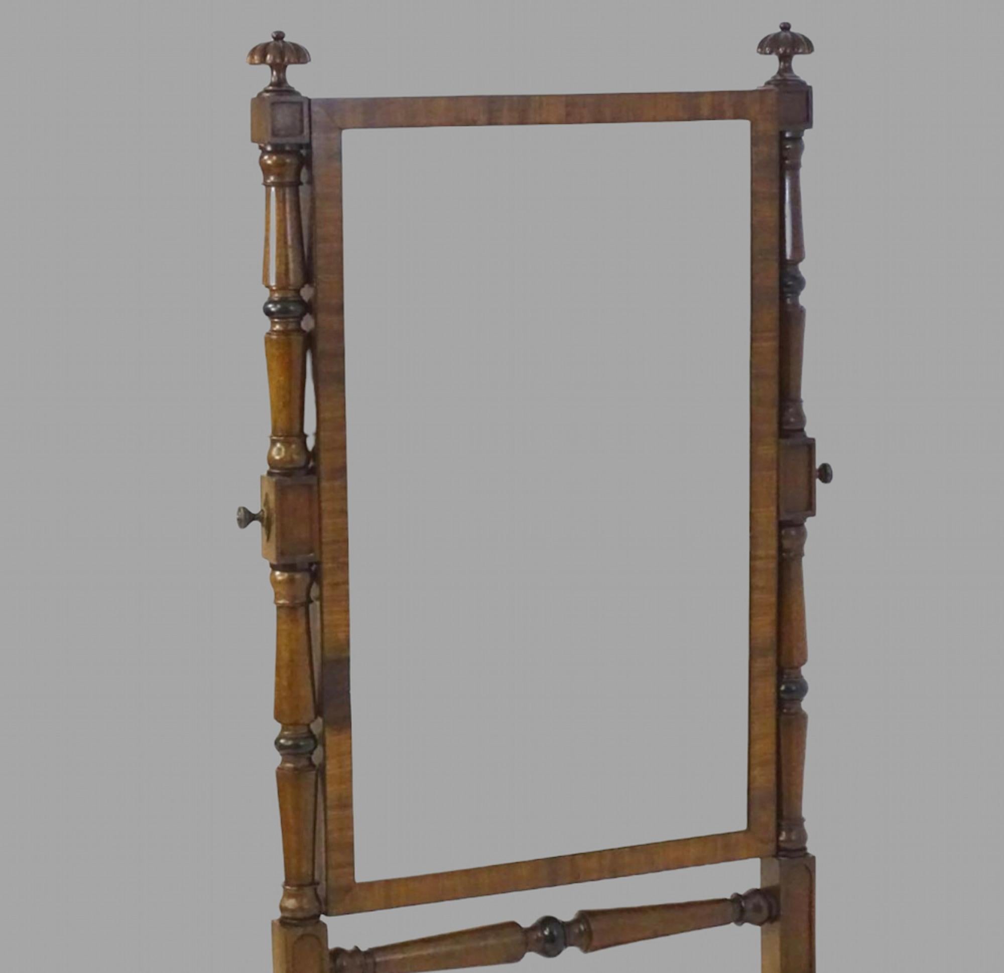 An early 19thc mahogany Cheval mirror surmounted by gadrooned finials above two turned tapering supports flanking a rectangular mirror and having four reeded cabriole legs supported by turned stretcher and castors.