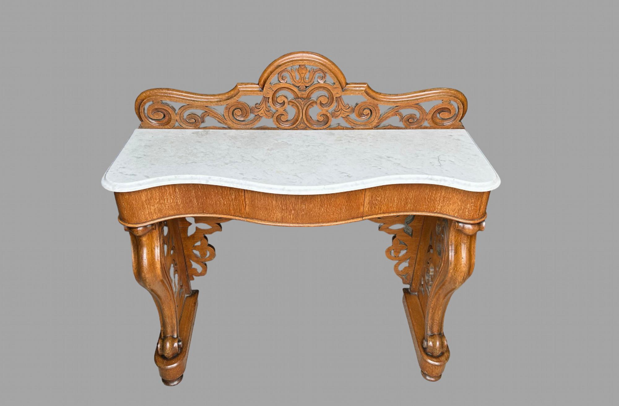 A Victorian Mahogany and Marble Topped Console Table. With a pierced back gallery and a serpentine shaped white marble small scratching commensurate with age. On a scroll leg base with pierced and lattice worked sides. The plan frieze with a single