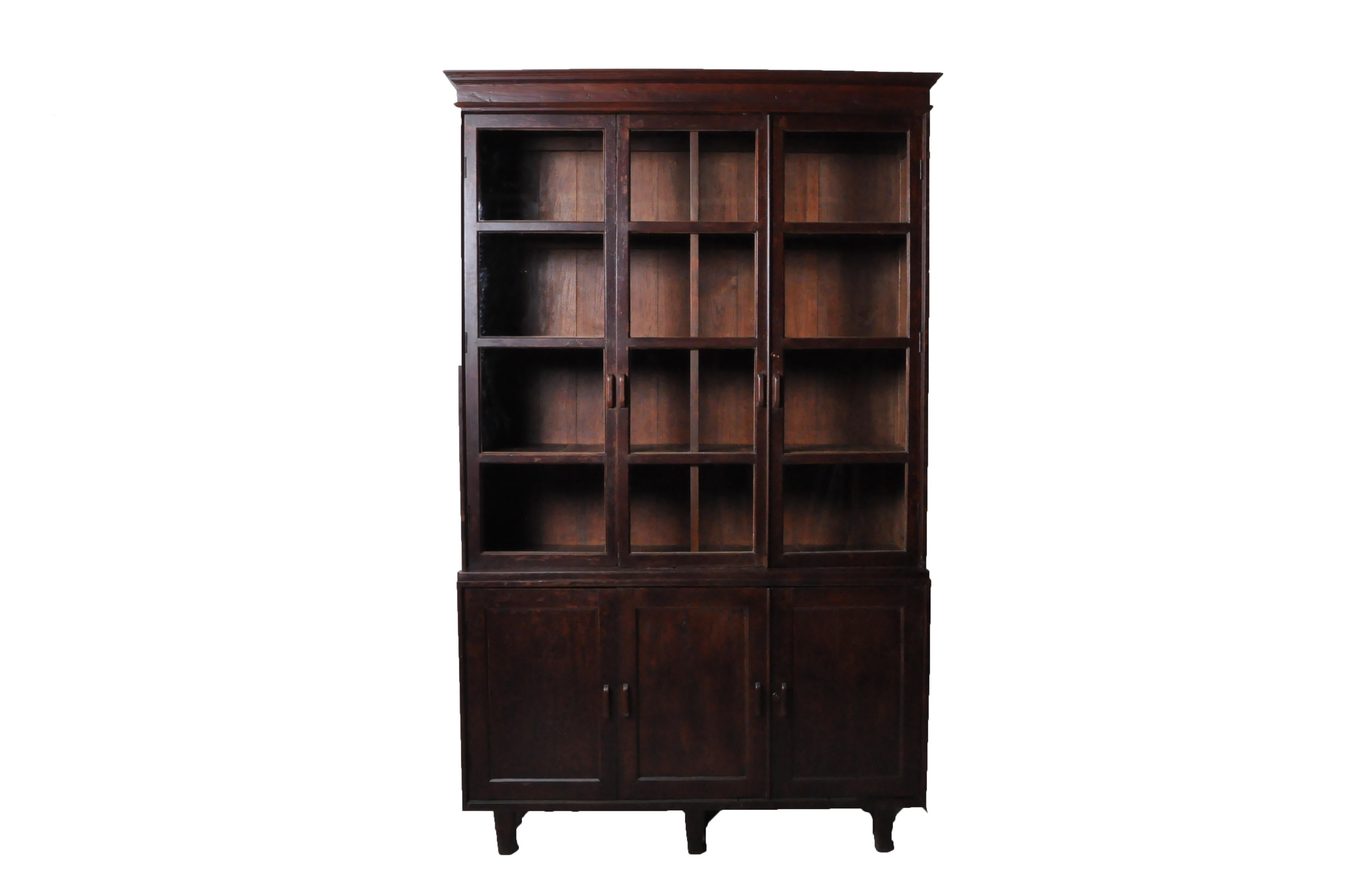 This impressively-scaled book cabinet was made from solid Teak wood and dates to the 1920's. During the late British empire in India and Burma much furniture was made in the Art Deco Style using local hardwoods and native furniture builders. Art
