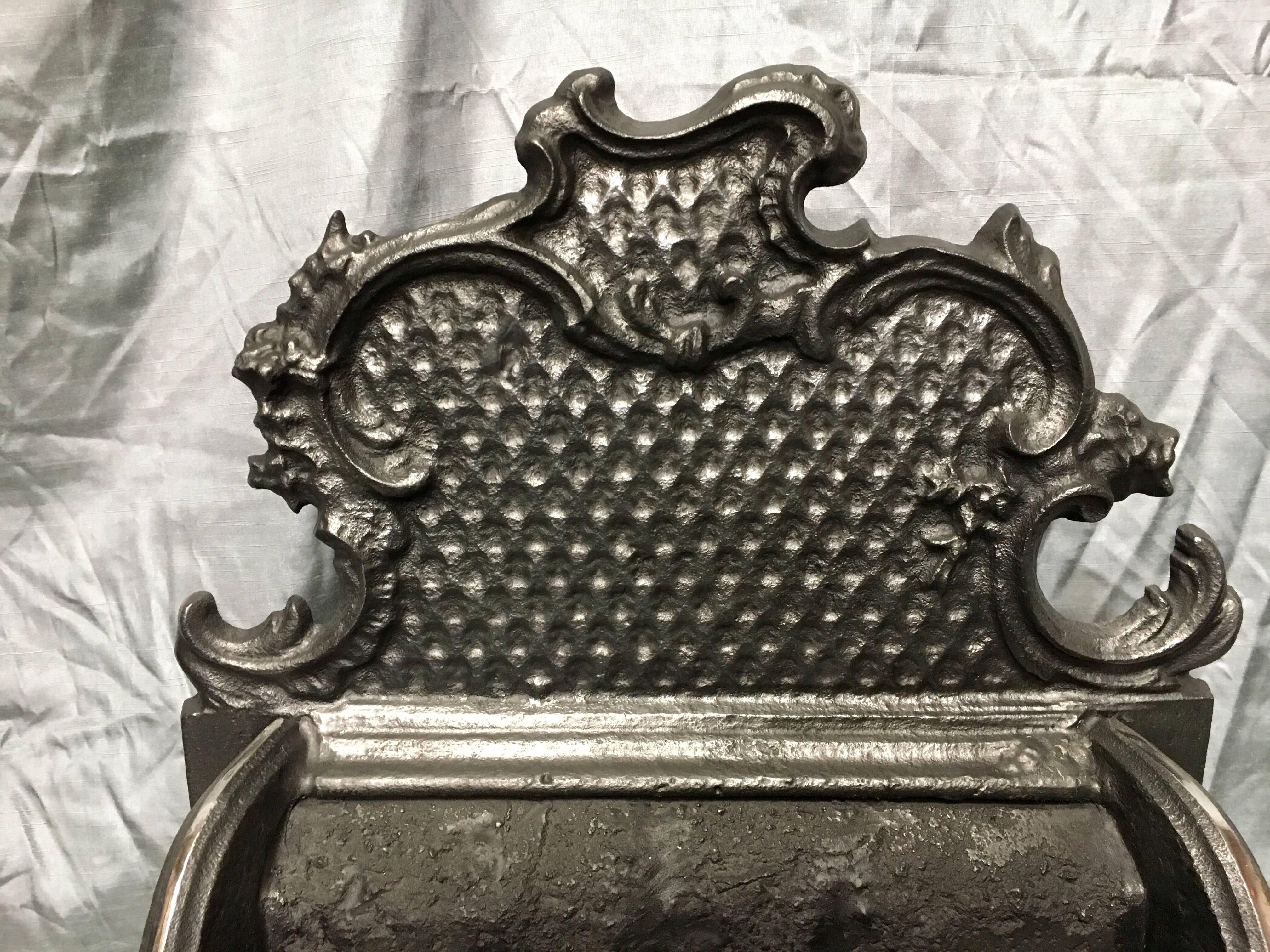 A period 20th century cast iron fire grate in the ornate 18th century English Georgian Rococo style of Thomas Chippendale. The tall 