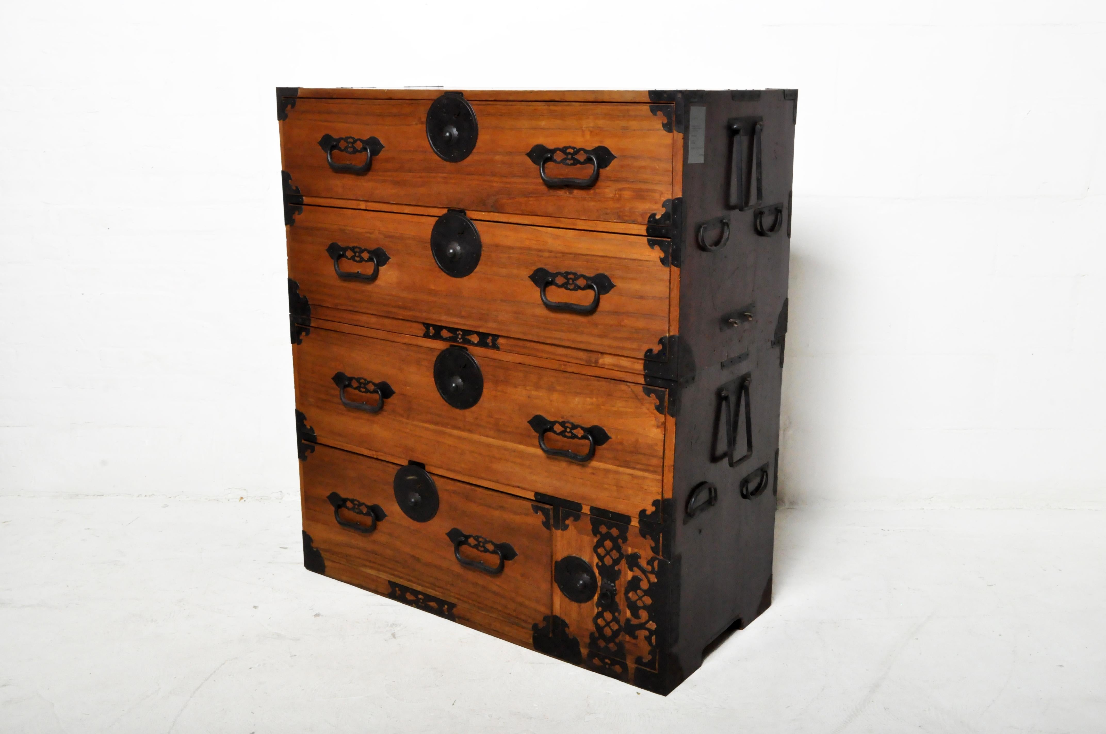 Crafted in Japan during the 20th century, this Kiri wood tansu chest is a fine example of Japan's traditional mobile cabinetry. The long side handles flip up to permit a pole to be inserted so the chest can be carried by two people. This portability