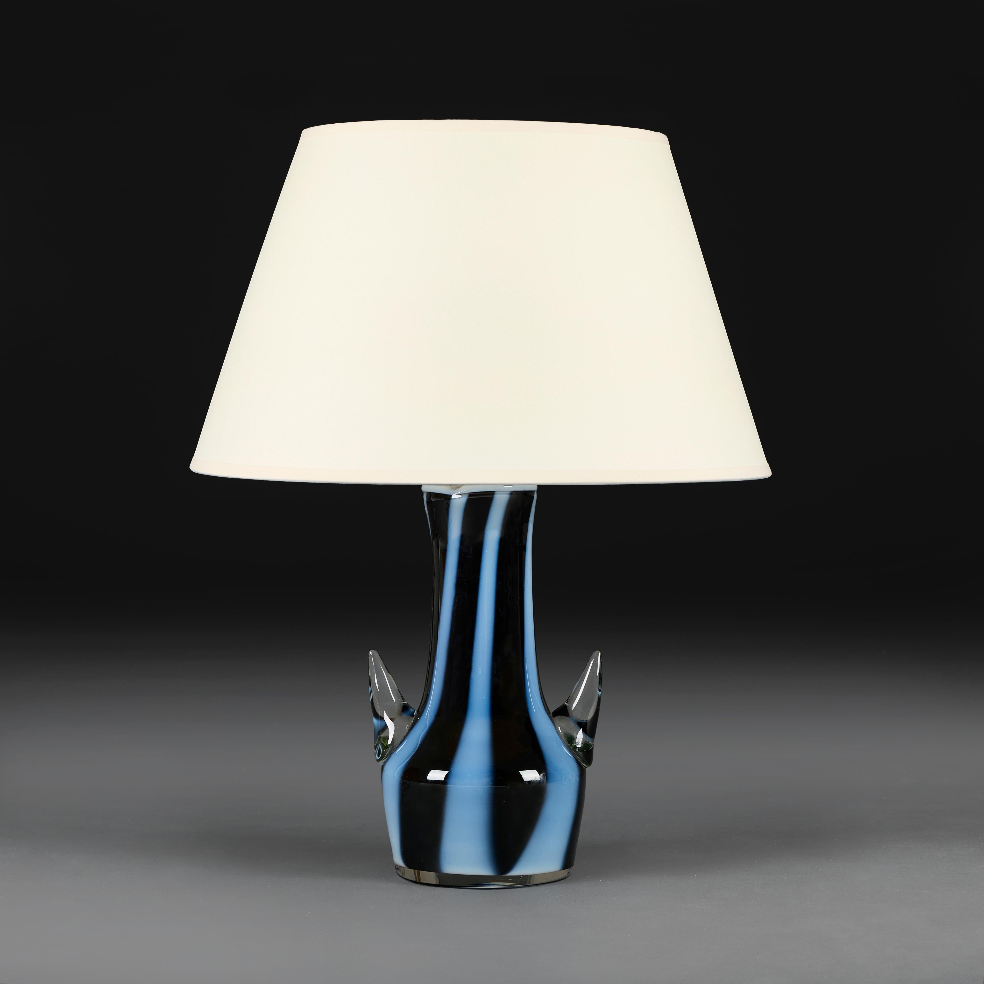 Italia, hacia 1960
Jarrón de cristal de Murano de mediados de siglo, con estilizadas asas en forma de pico, con franjas azules y negras en toda su superficie y borde blanco, ahora montado como lámpara.

Altura del jarrón               28.50cm
Altura