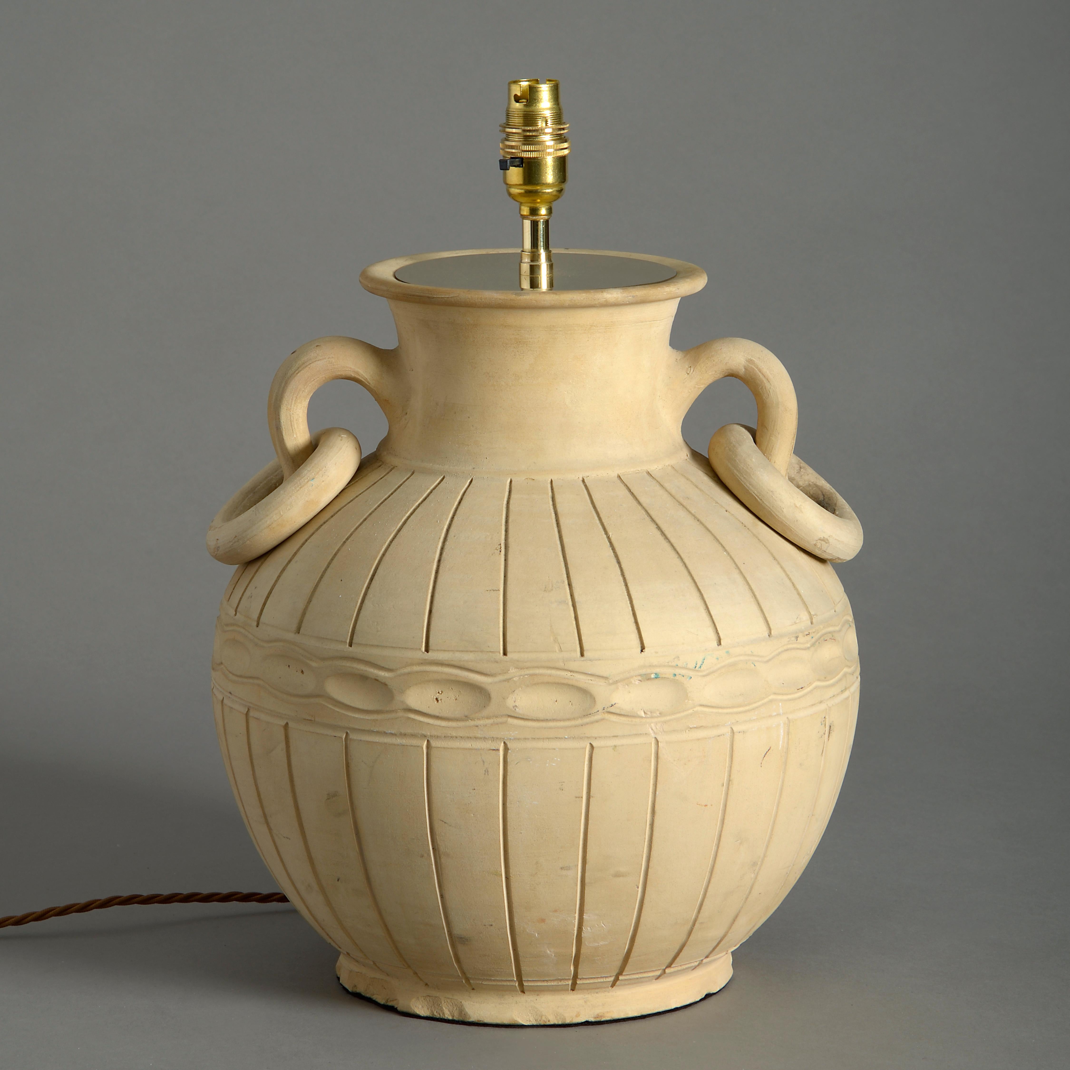A mid-20th century terracotta vase of Classical form, the bulbous reeded body with ring handles.

Dimensions refer only to terracotta vase and exclude electrical fittings.

 