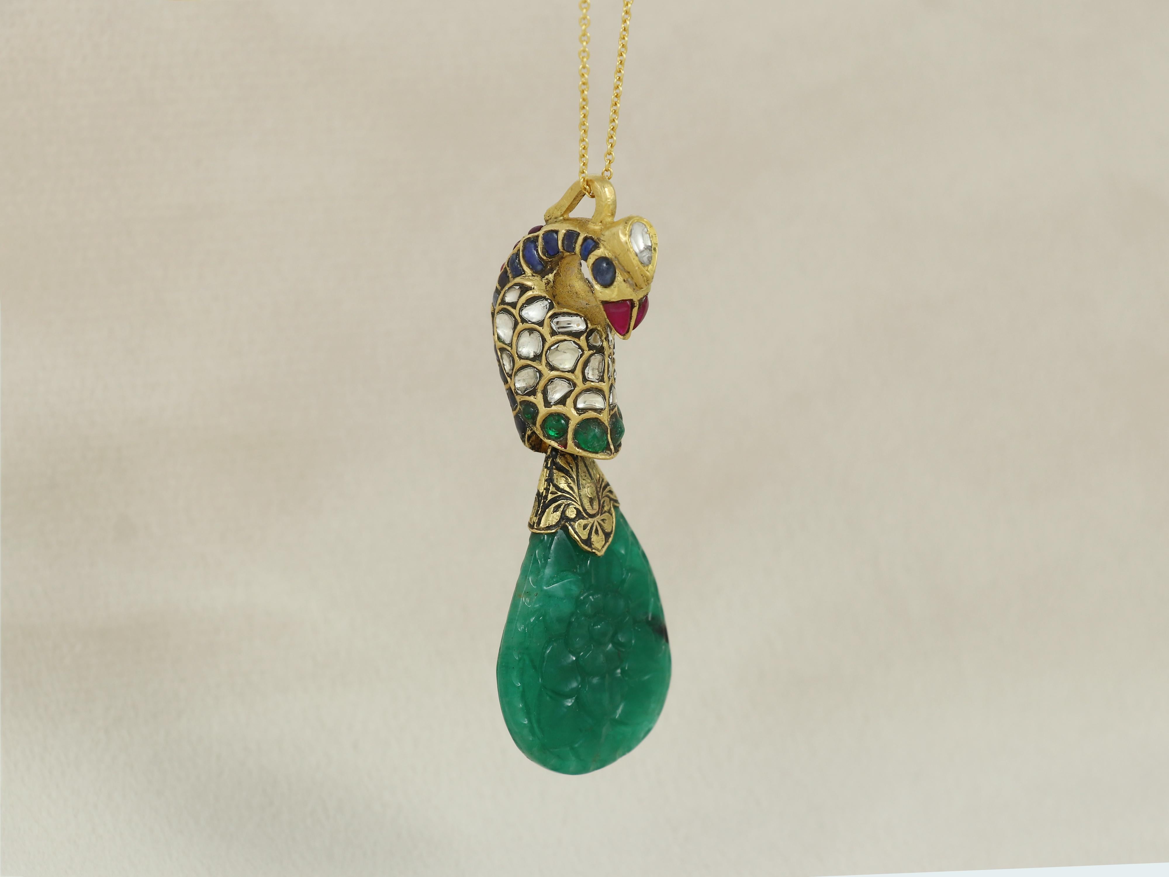 Set with a 40ct carved emerald as tail, this pendant is adorned with diamond polkis and small reshaped emerald and rubies set inside a 22K gold casing.

The craftsmen has meticulously crafted a full body peacock in gold and has set it with all kind