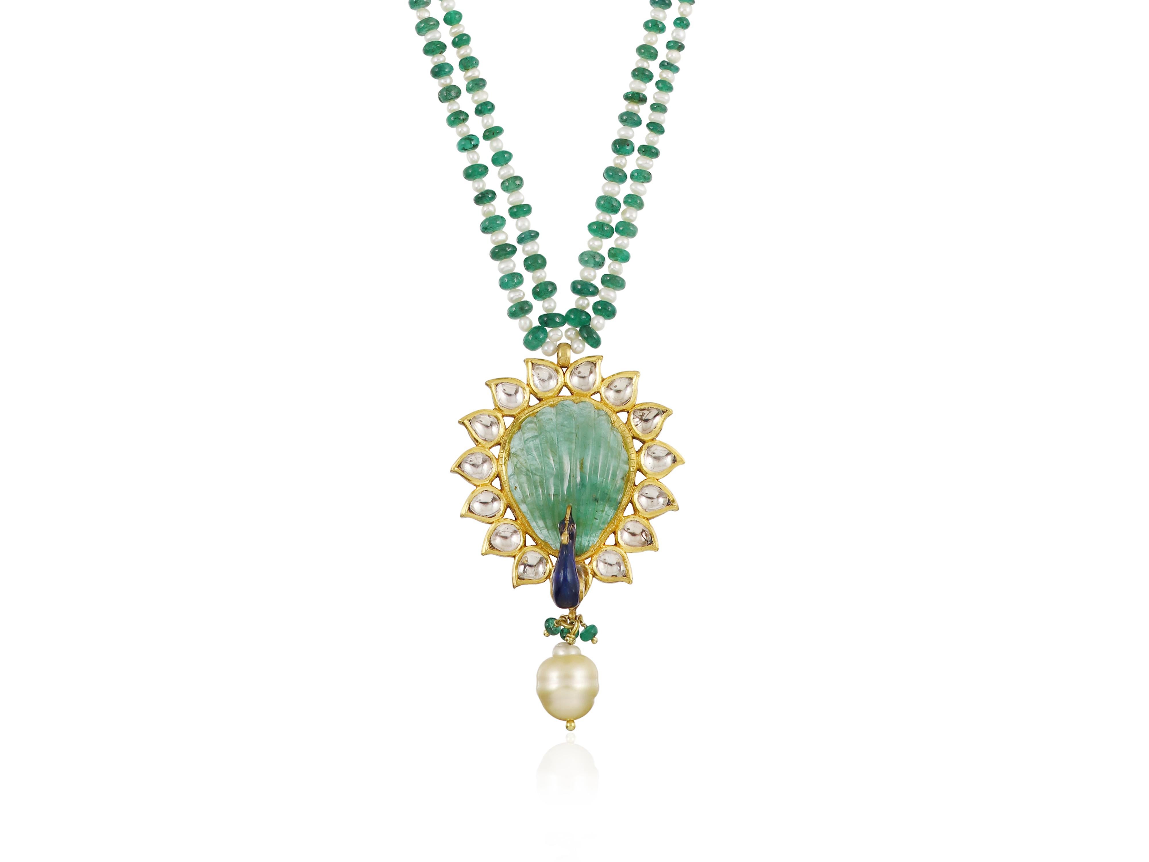 Set with a carved Zambian emerald piece this 22K gold pendant in shape of peacock is set with top quality natural flat uncut diamond polkis.

Surrounded with petal shaped polkis the carved Zambian emerald has been set in an open black enclosure to