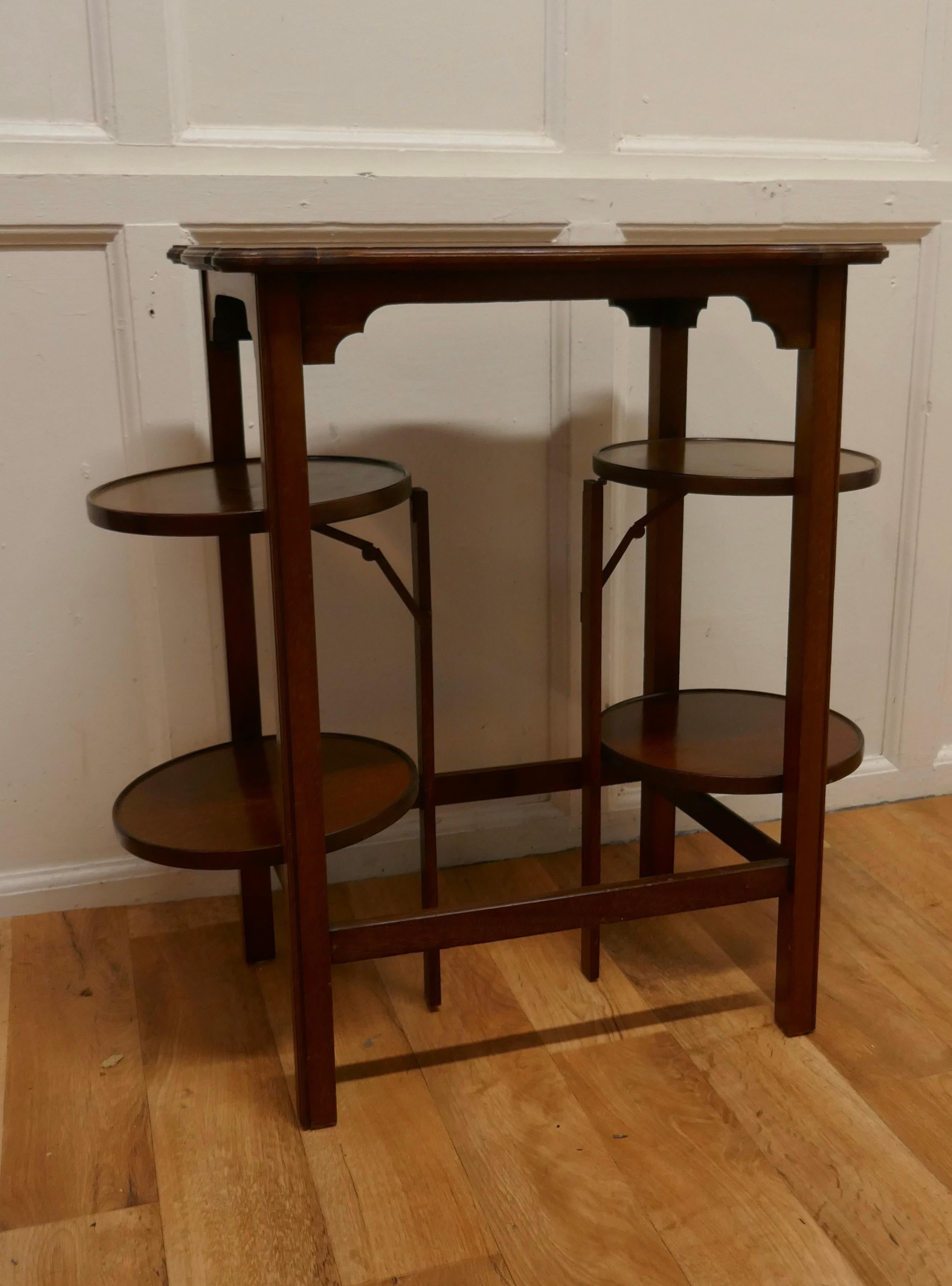 A 4 Tray Mahogany Table Cake Stand or Dumb Waiter 

A charming and unusual piece is in good condition, it is a central rectangular table with a scalloped edge which has 2 round cake trays which fold out from both sides
The stand is in excellent