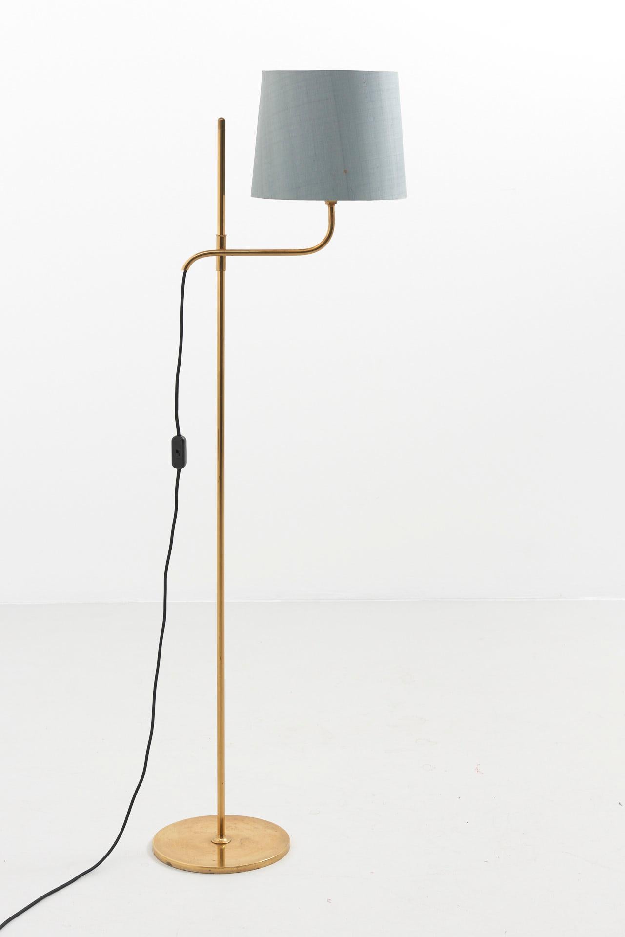 A floor lamp in brass with light blue lamp shade. Adjustable in height. Design by Florian Schulz, made in Germany.