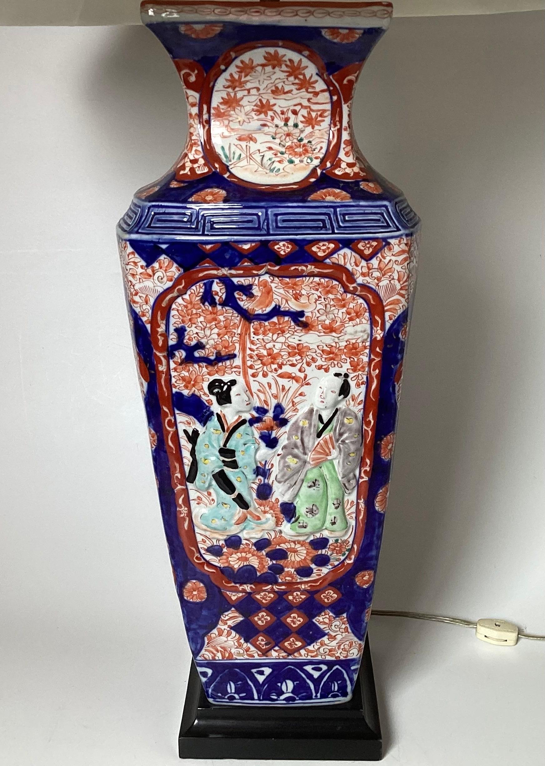 Un grand vase Imari aux couleurs vives datant de 1880 puis électrifié dans les années 1920. Les classiques rouge fer et bleu cobalt sur fond blanc avec des représentations en relief de couples en train de se faire la cour avec une décoration florale