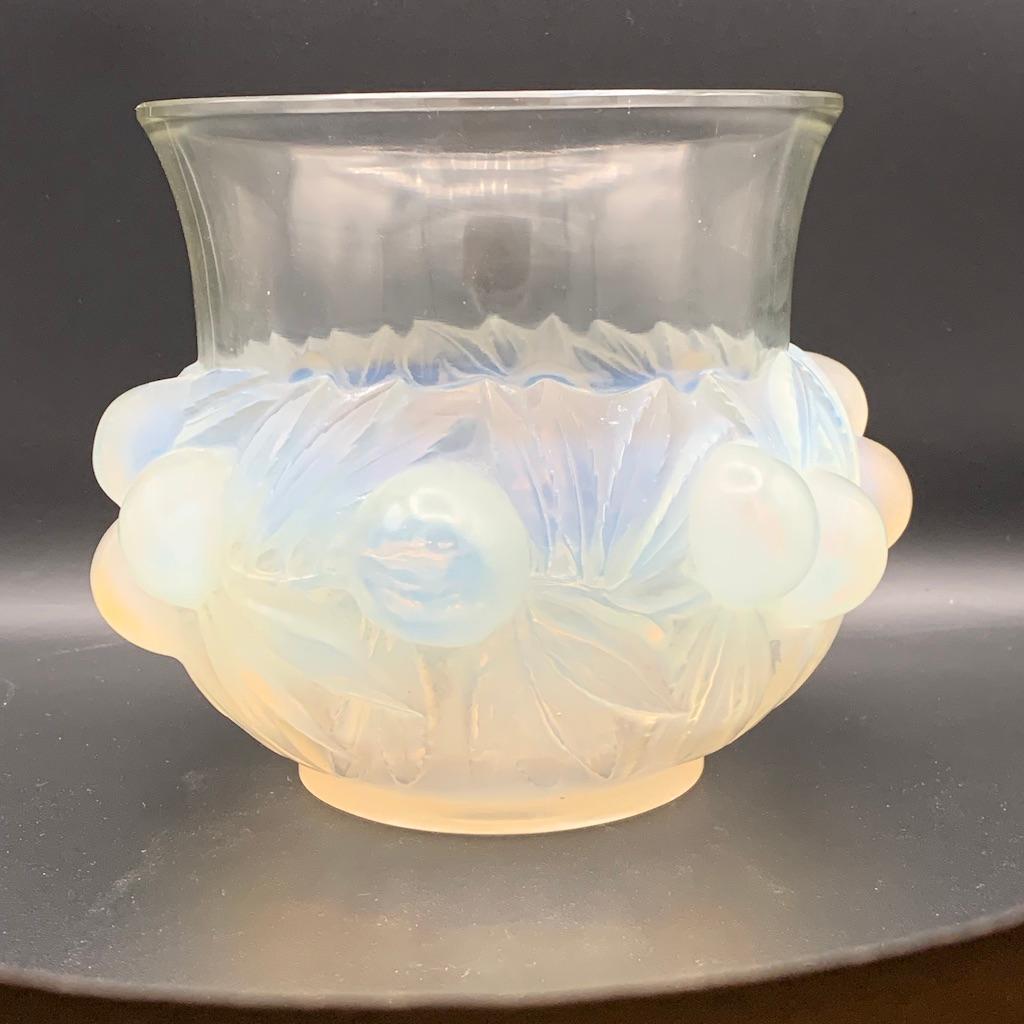 The Prunes vase is a larger than high vase with vat and rounded prunes around the base .

The opalescence is deep on the fruits and plays with blue and yellow colors  on them.

The neck still has an opalescence in the glass and is finished with a