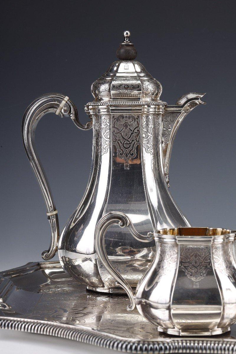 Important TEA/COFFEE service in solid silver, model with a flat bottom, with pinched ribs, each piece is chiseled with a berain decoration, interlacing on amati background and gadroon borders, zoomorphic spouts. It is composed of a coffee maker, a