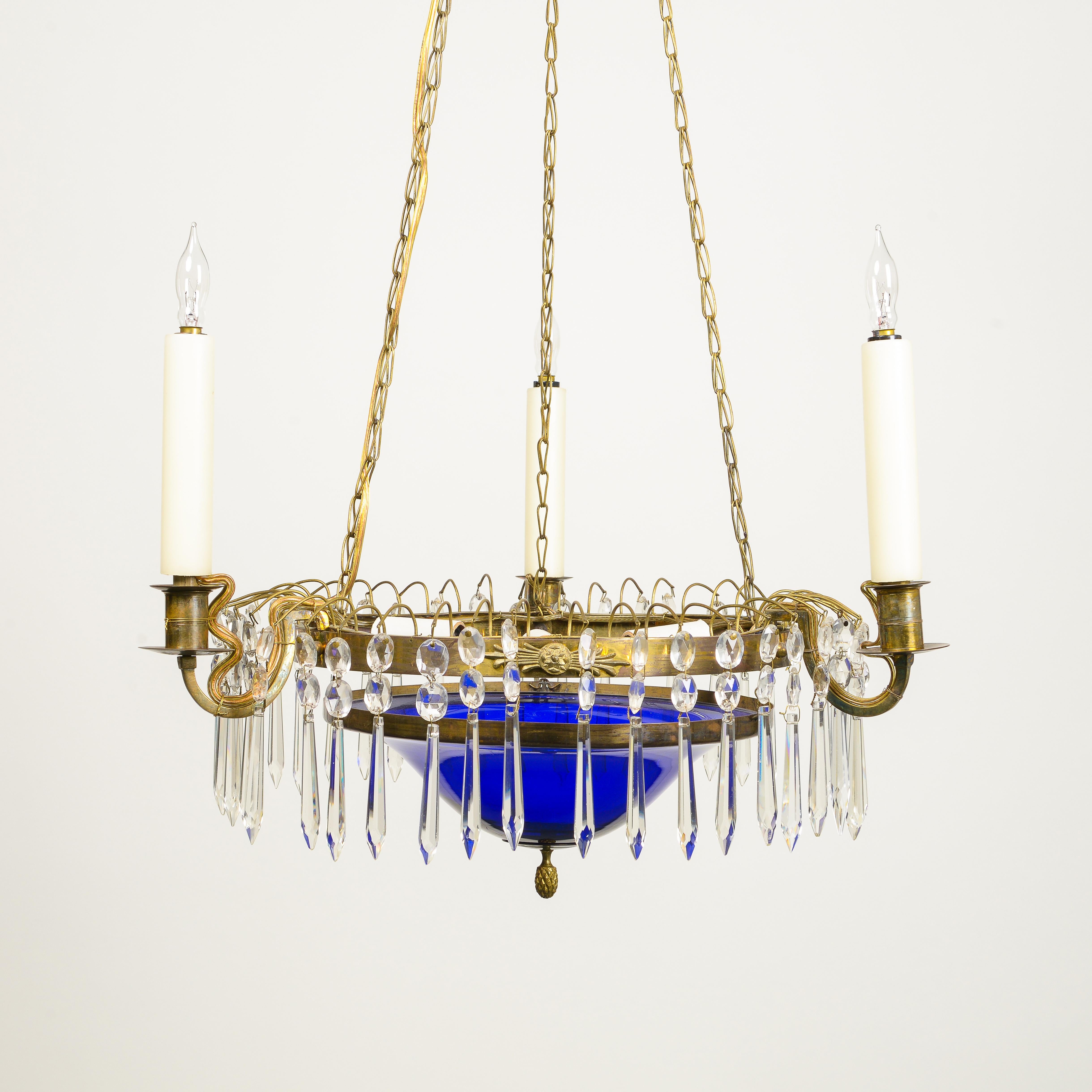 With round cobalt glass bowl trimmed in gilt bronzel banding and issuing three electrified candlearms; suspended by three gilt-bronze chains hung from a disk issuing sprays of cut glass pendants. With three bulb sockets to the interior; requires 5