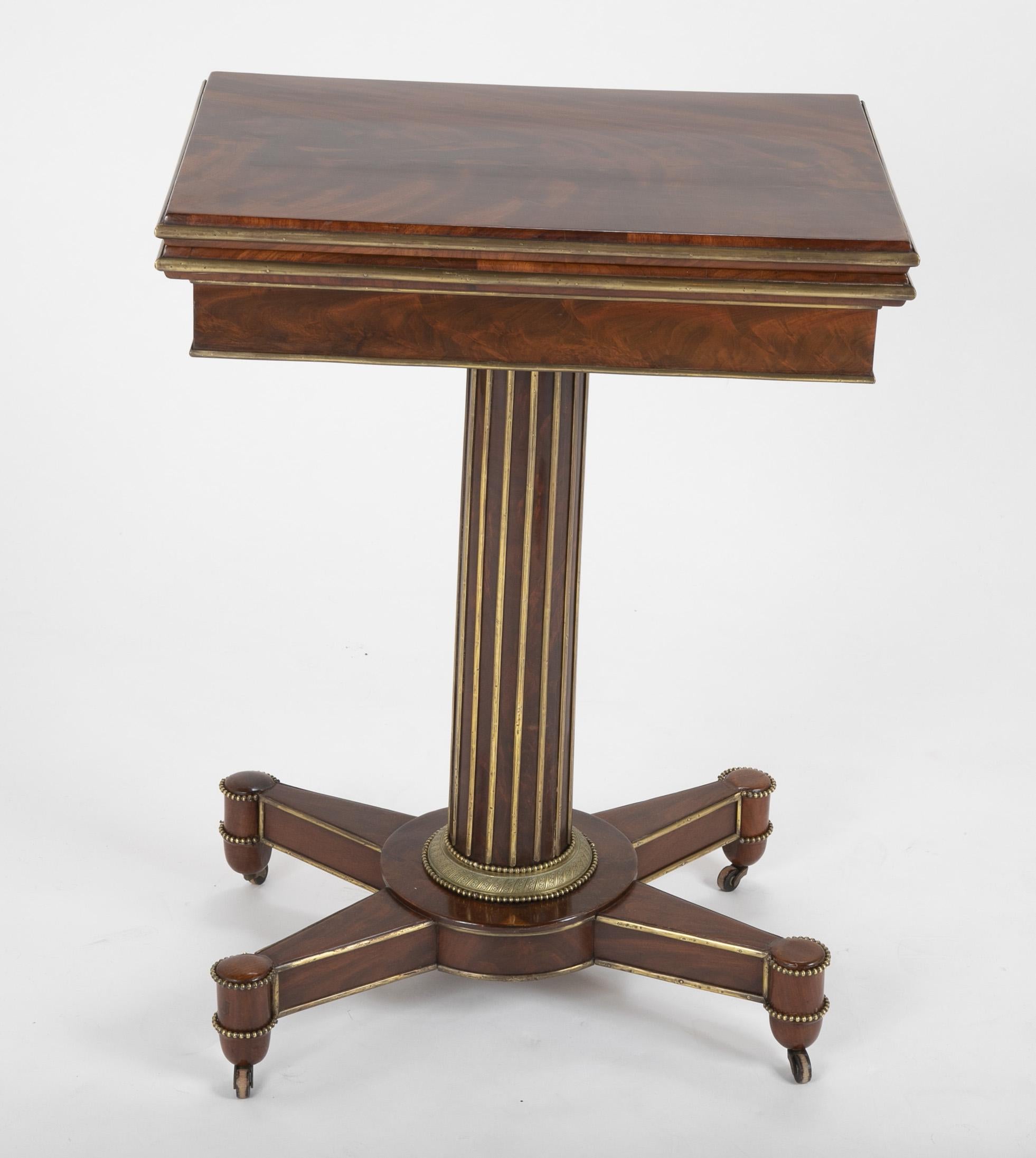A Northern European Empire games table. Flamed mahogany top opens to reveal felt lined game surface. Brass mounts embellish a neoclassic sensibility.