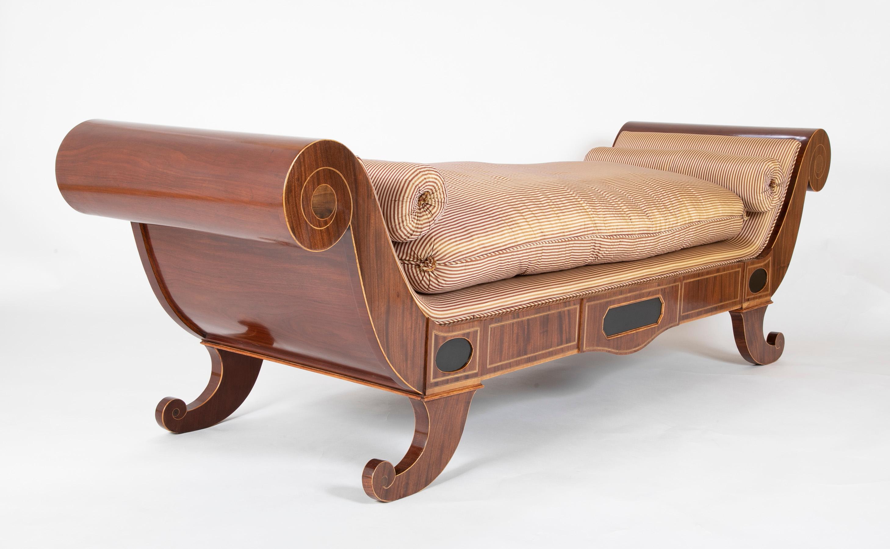 A 19th century mahogany and fruitwood baltic daybed. Having scroll form sides with central ebonized panel. Upholstered in stiped silk fabric.