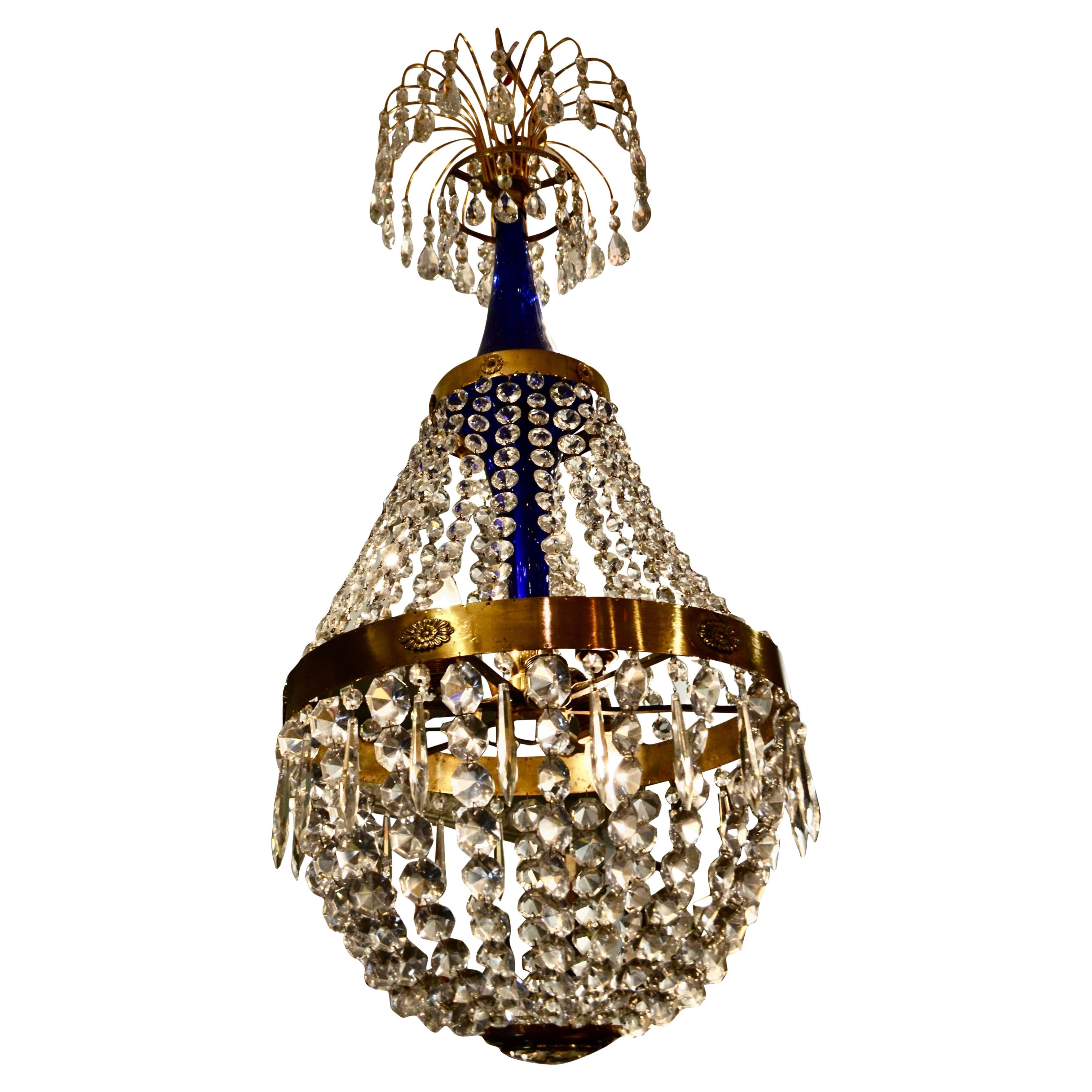 The chandelier embodies some of the best design features of early 19th century Russian/Baltic chandeliers, featuring cobalt blue glass around the central stem; a top spray of curved gilded rods terminating in almond and round shaped cut crystals; a