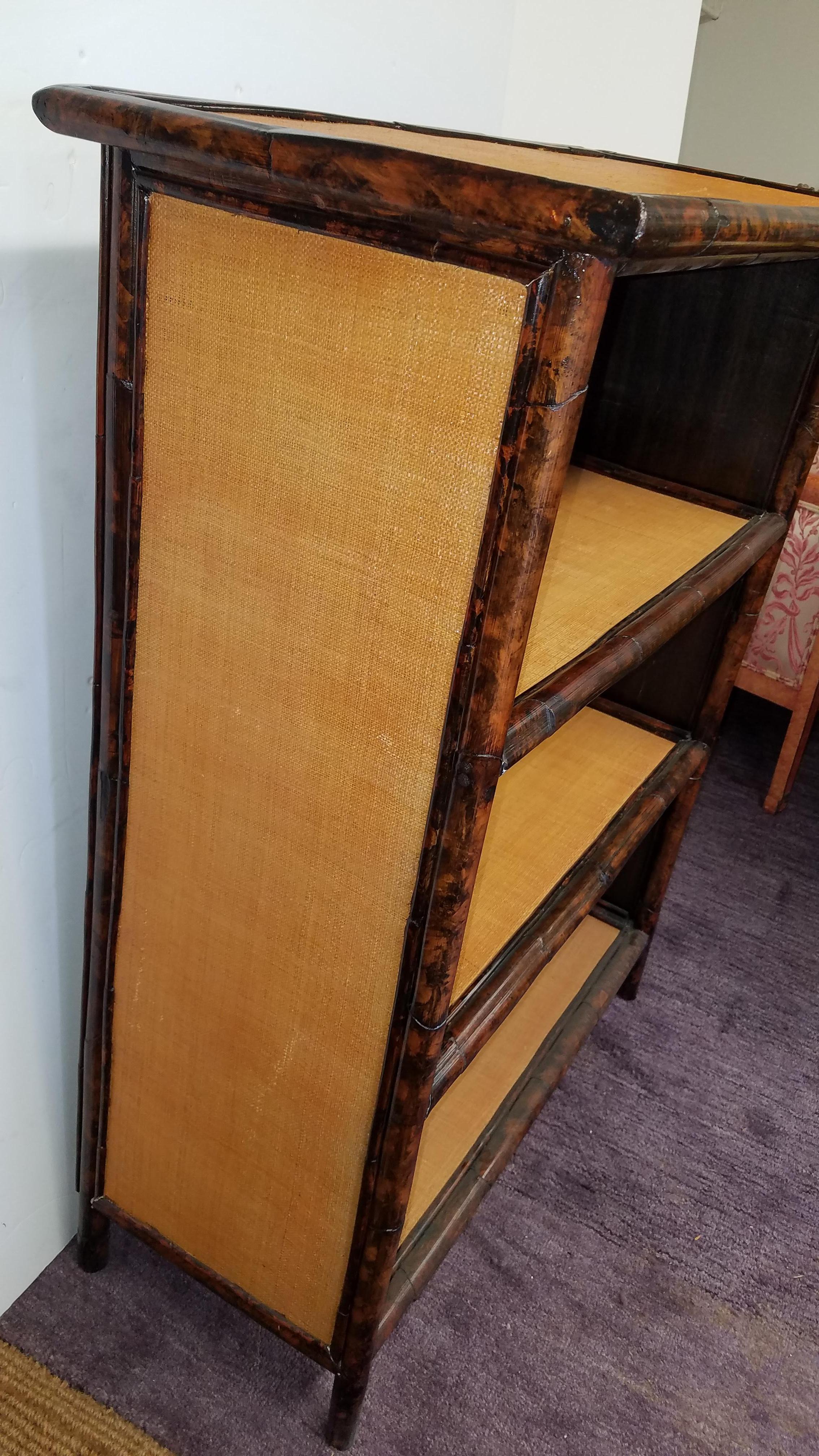Highly decorative Englis Chinoiserie bamboo and grass cloth bookcase. The three shelves, each 12 inches apart. Very clean and excellent quality 42.75 inches tall, 33 inches wide, 15.5 inches deep.