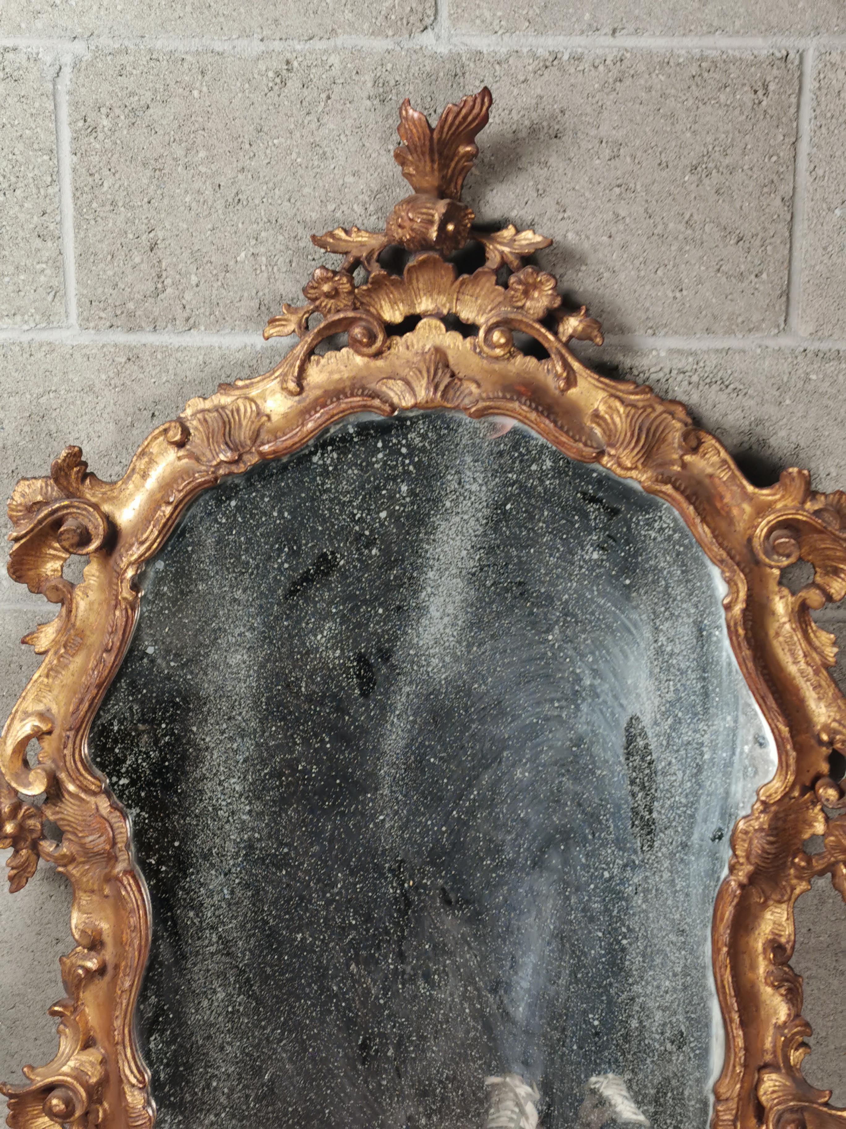 A Magnificent Venetian gilded wall mirror about 1750-1770 Italy. Very particular piece. 
Measures: 75 x 110 cm. Will be shipped inside a secured wood box. 
Mirror frame is in very good condition. Glass part is original and there are signs of agings