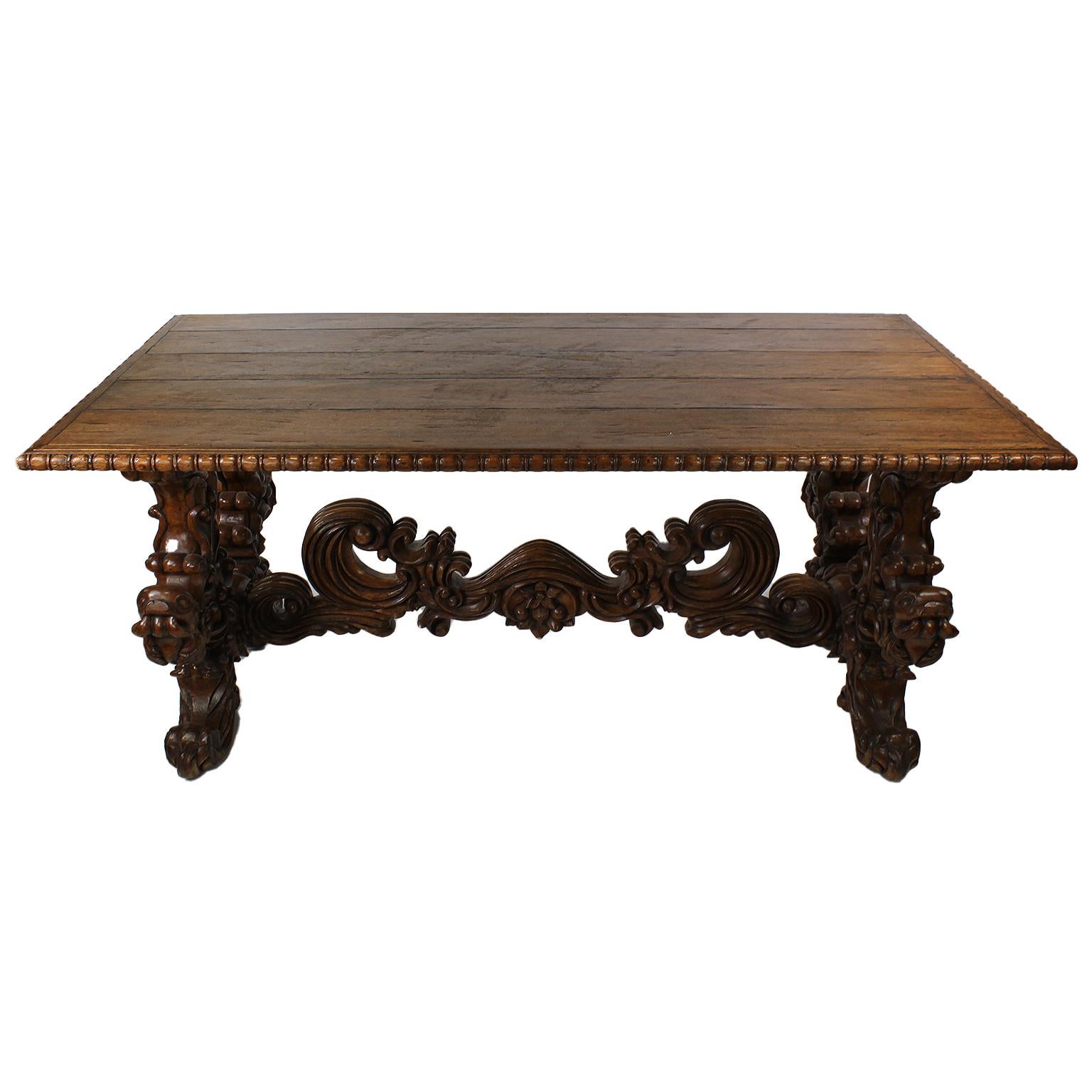 A large carved wood tavern or farm dining table in the Baroque Revival Style. The rectangular top with a carved border, raised on twin carved pedestal bases conjoined with a central stretch-bar, probably Italian, but origin unknown. A great table