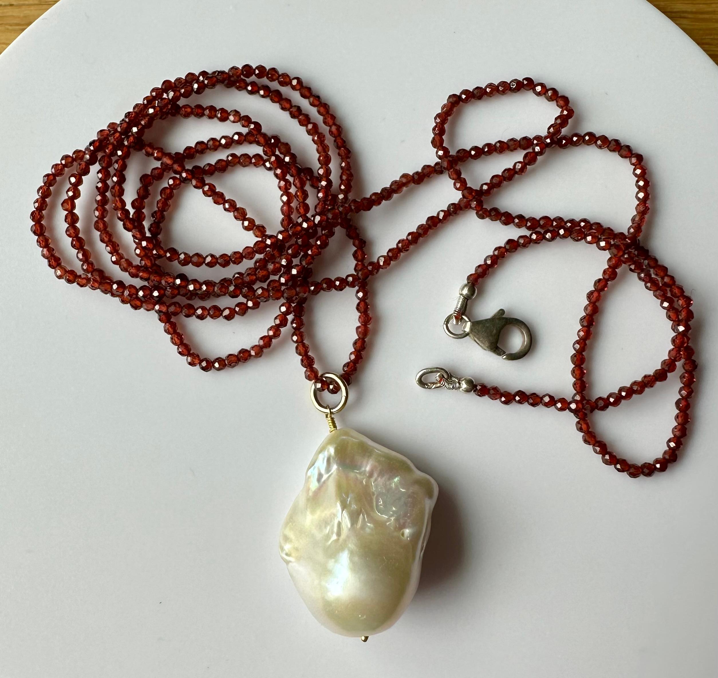 A large lovely Pearlescent Baroque Pearl Pendant hanging from a 24 Inch Beaded Garnet Necklace. The faceted Garnet Beads scintillate and sparkle as the light plays over their facets. This lovely Baroque South Sea Pearl has amazing luster and shows