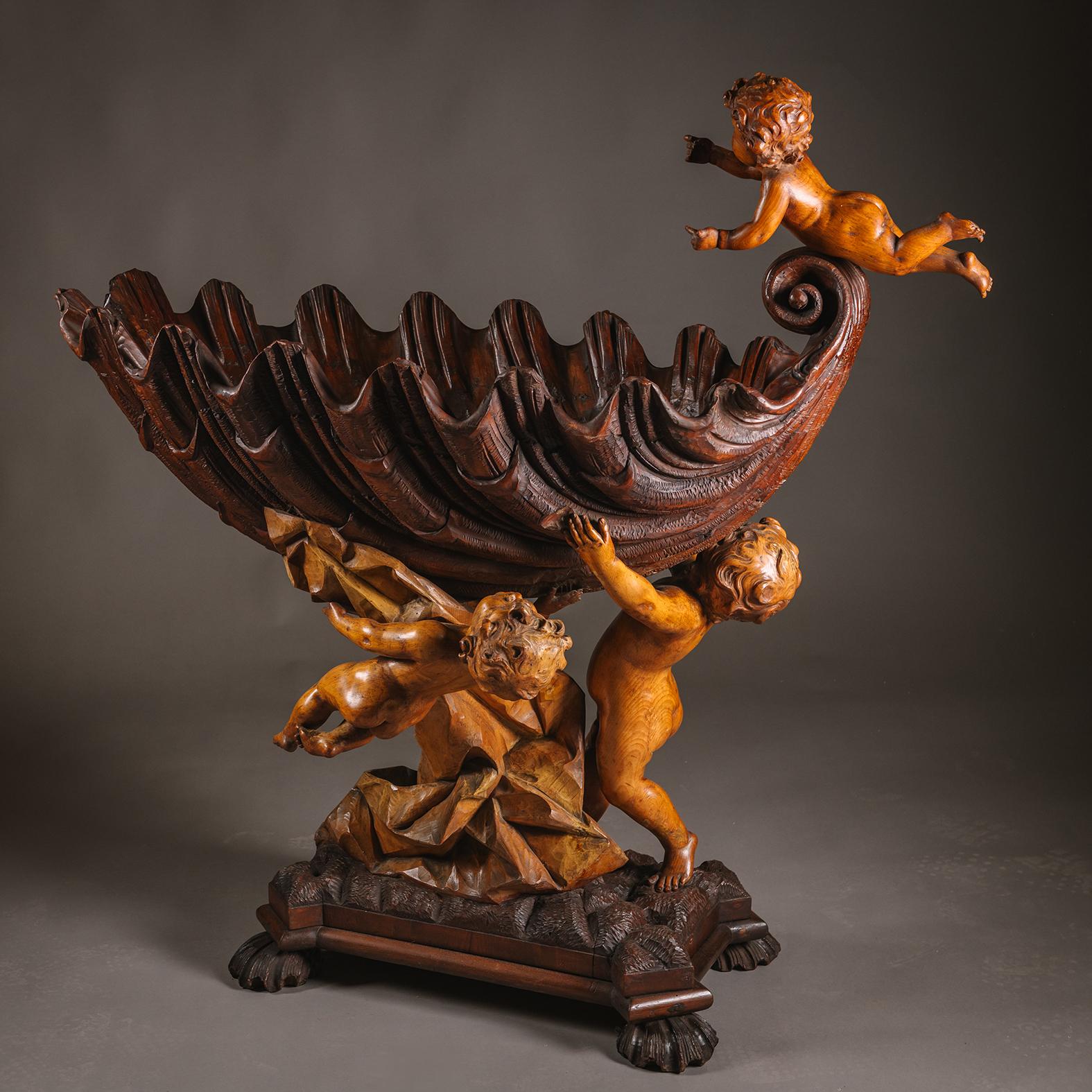Berceau en bois sculpté de style baroque. 

La coquille de forme ovale avec un fleuron à volutes est surmontée d'un putto en vol. Le dessous de la face avant avec un putto grimpant. La coquille est tenue par un putto debout, les bras levés, sur un