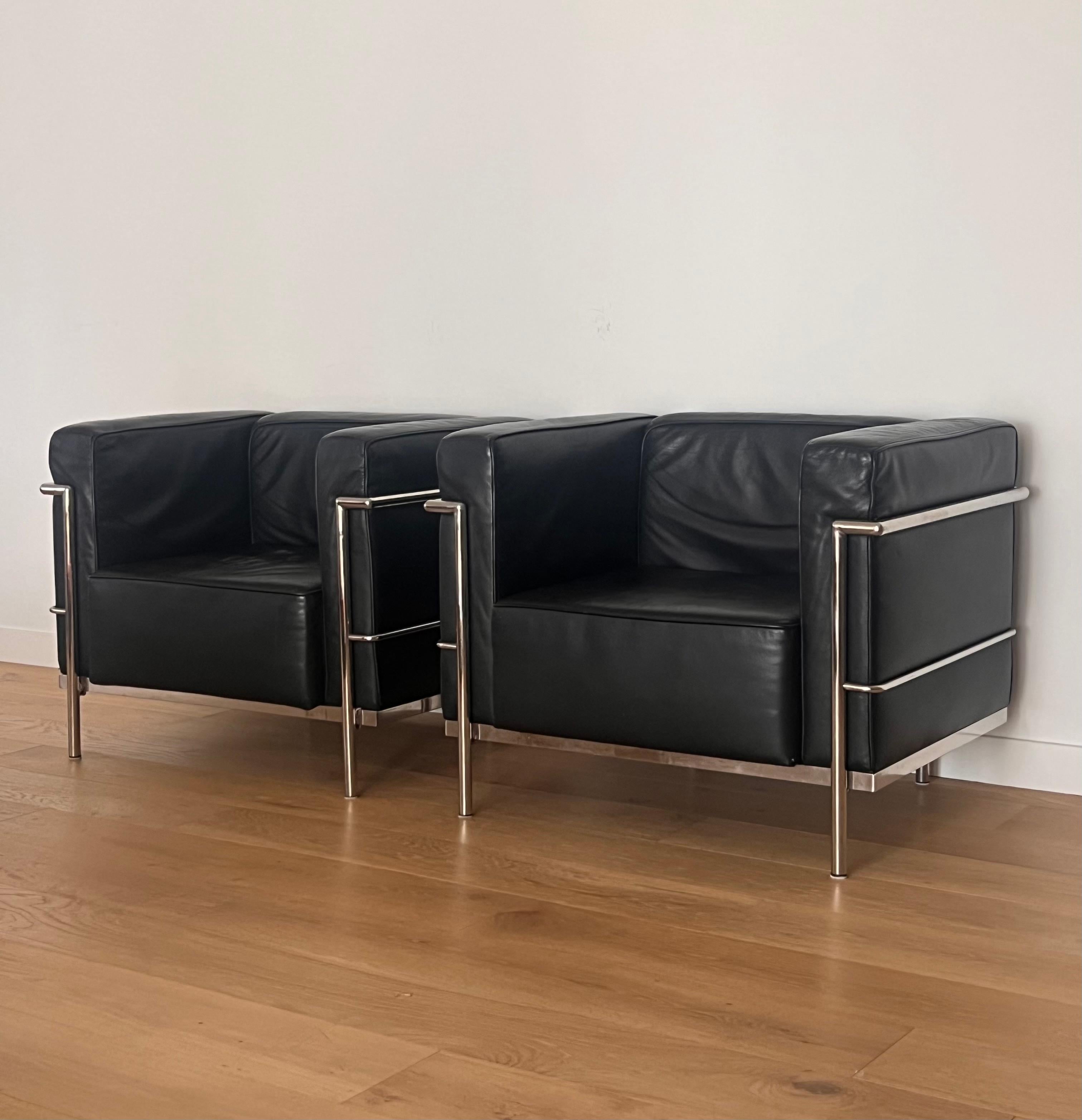 A vintage pair of Bauhaus Lc2 club chairs designed by Le Corbusier, Pierre Jeanneret, and Charlotte Perriand, 20th century. Black leather encased in chrome frames. Designed initially in the 1920s, these chairs were later reproduced by Design giant