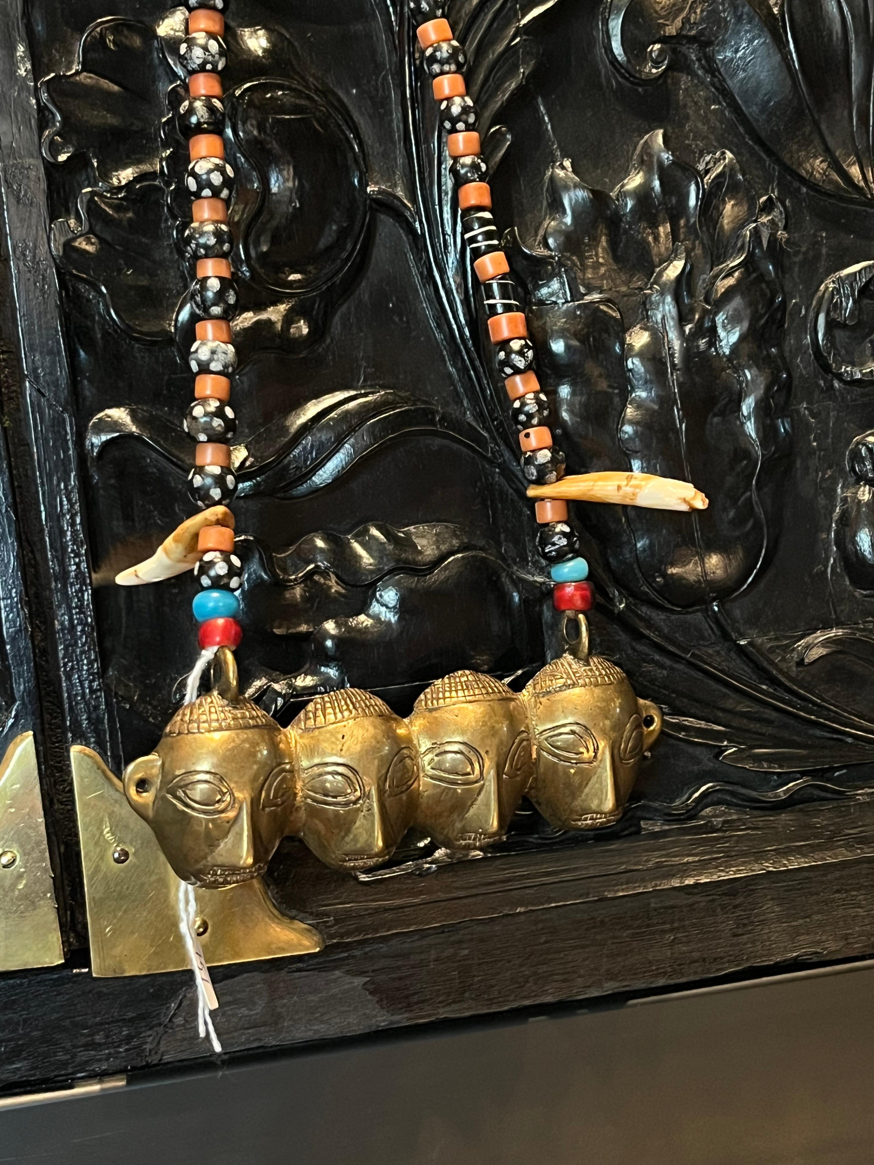 Nagaland, North-east India, early 20th century

A necklace comprised of glass beads, two dog tooth and a brass face pendant. The four headed pendant symbolises decapitated head-trophies from the Naga headhunters.

The Naga people, a variety of