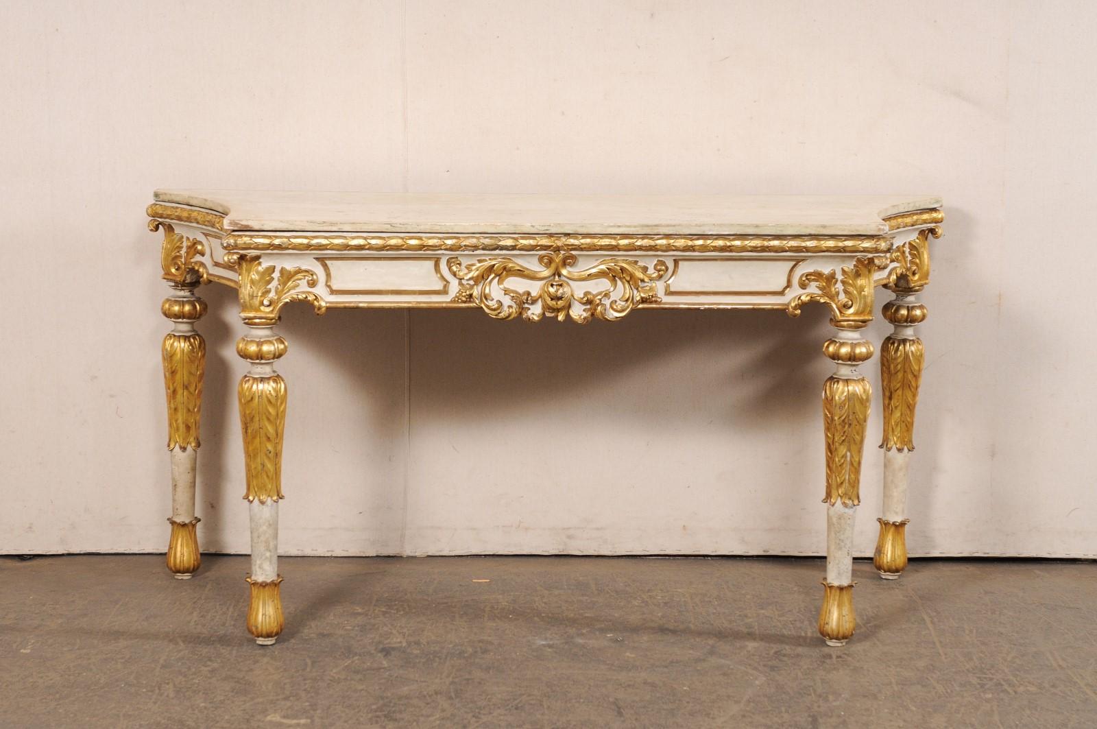 A beautiful Italian carved and gilded console table, nicely-sized with a robust presence, from the 18th century. This antique table from Italy retains its original marble top, which is shorter along the front side, giving way to nicely scalloped &