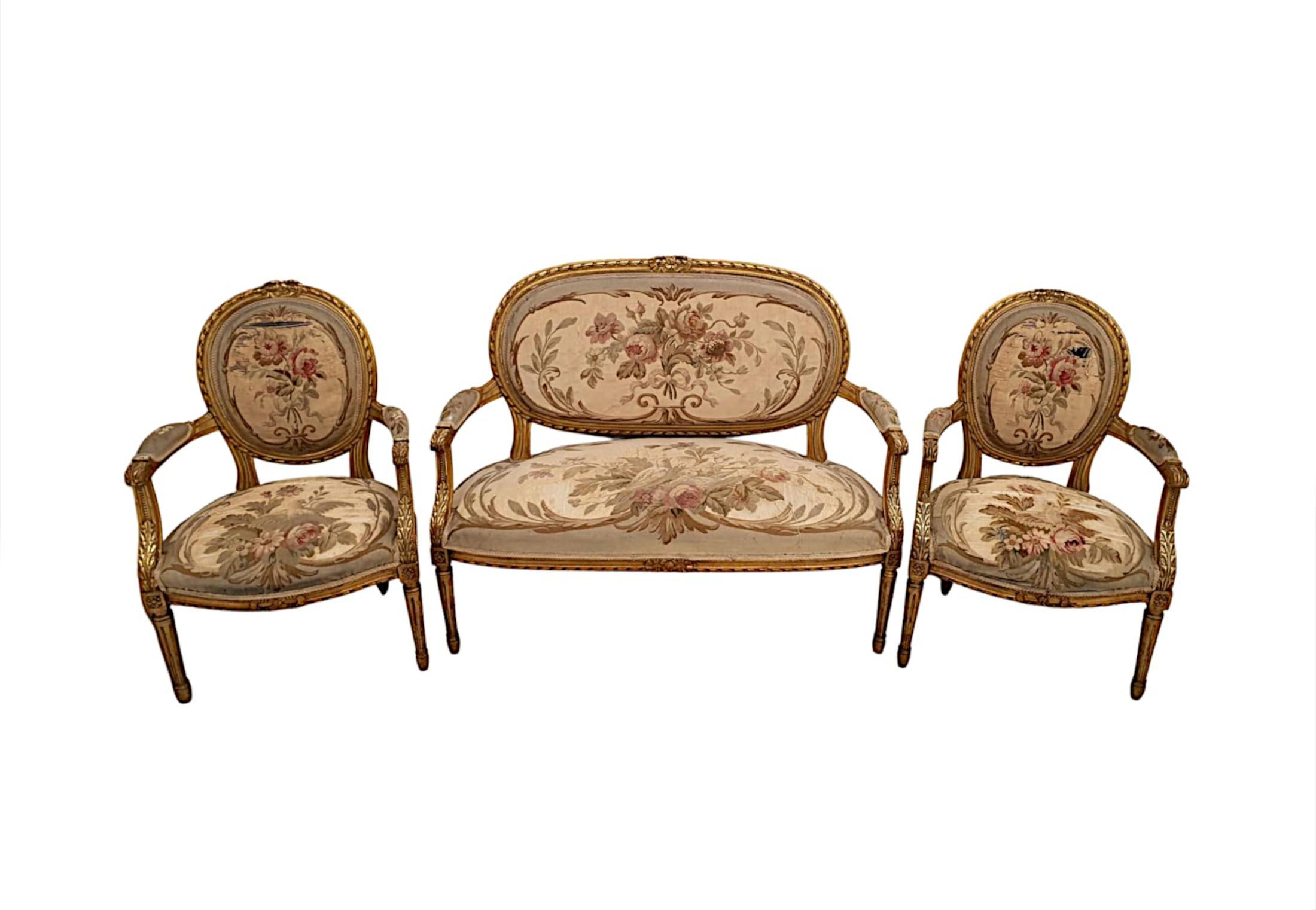 A beautiful 19th century giltwood suite of neat proportions and fabulous quality, comprising of a two seater sofa and two matching armchairs, upholstered in silk with delicate trailing foliate and flowerhead pattern detail in delicate hues of pink,