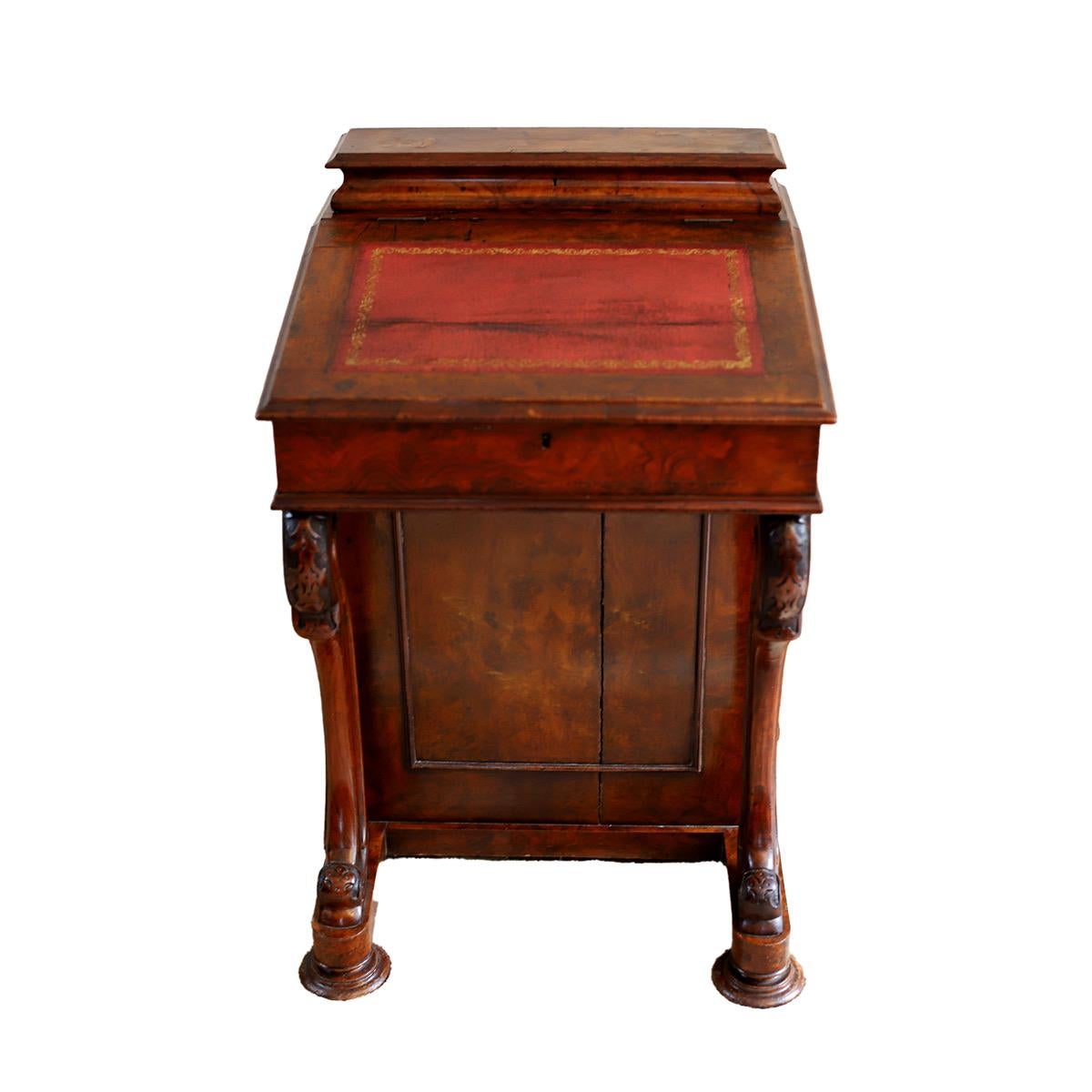 A Beautiful early-Victorian walnut Davenport fitted with four side drawers and raised on carved scroll supports.With a lift lid desk with 2 internal drawers and 4 drawers to one side and dummy drawers to the opposite side. To the top there is a lid