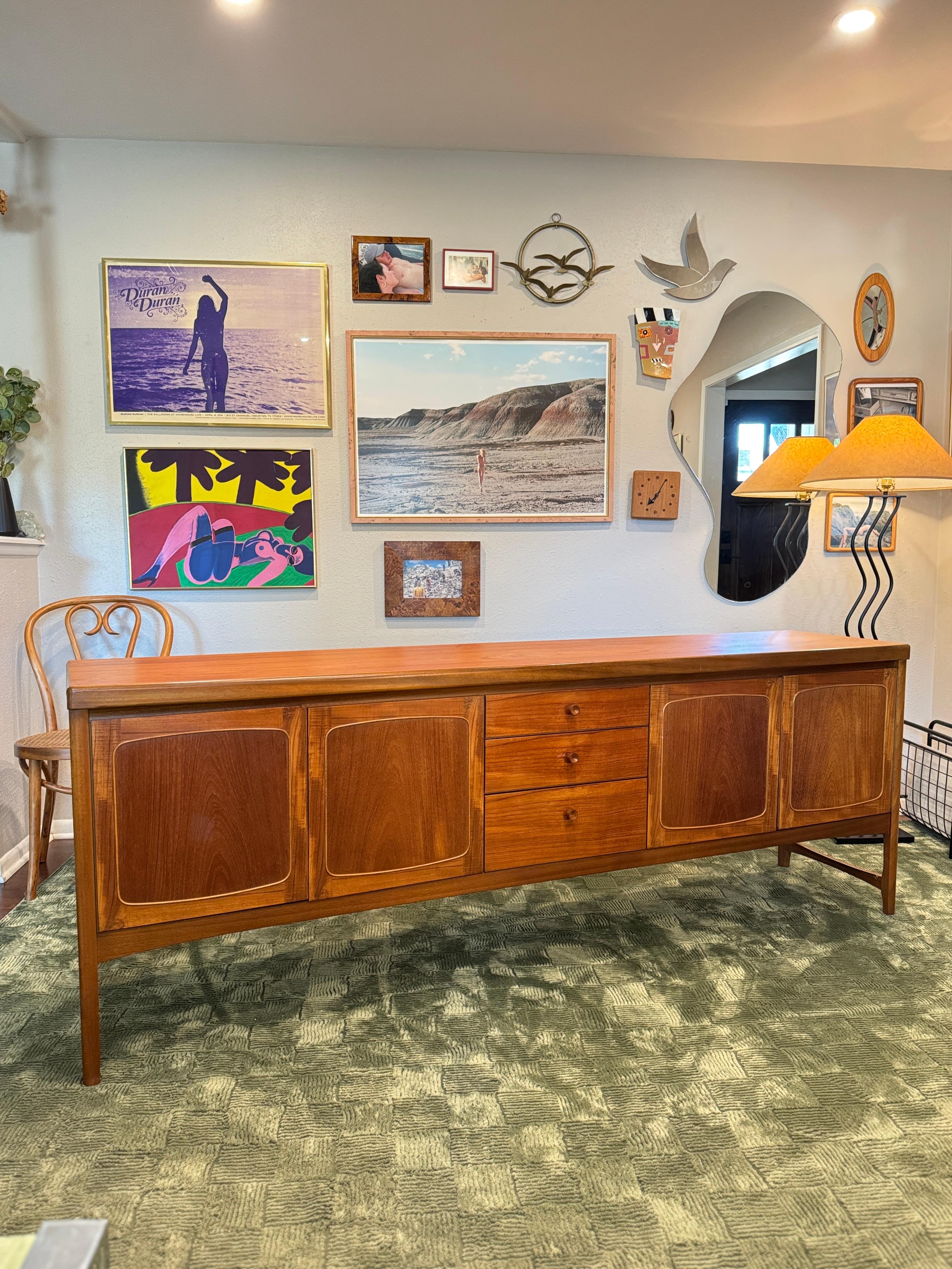 A beautiful, extra long teak sideboard by Nathan Furniture, called “Squares.” Made in the UK circa the 1960s, it features elegant doors with a square design, sculpted wood knobs, graceful legs with a stretcher between the front and back, and a