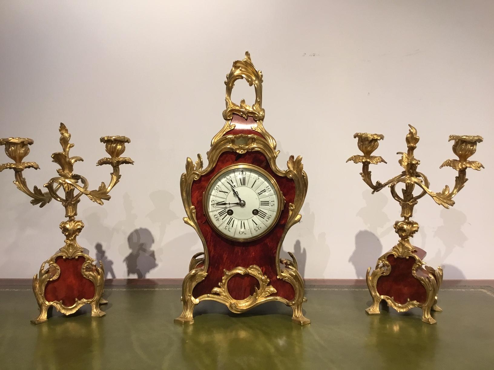 A beautiful late 19th century French tortoiseshell and ormolu clock garniture. The clock having an enameled Roman numeral dial with a typical French movement and striking a bell. Having an ormolu and tortoiseshell case with matching two branch