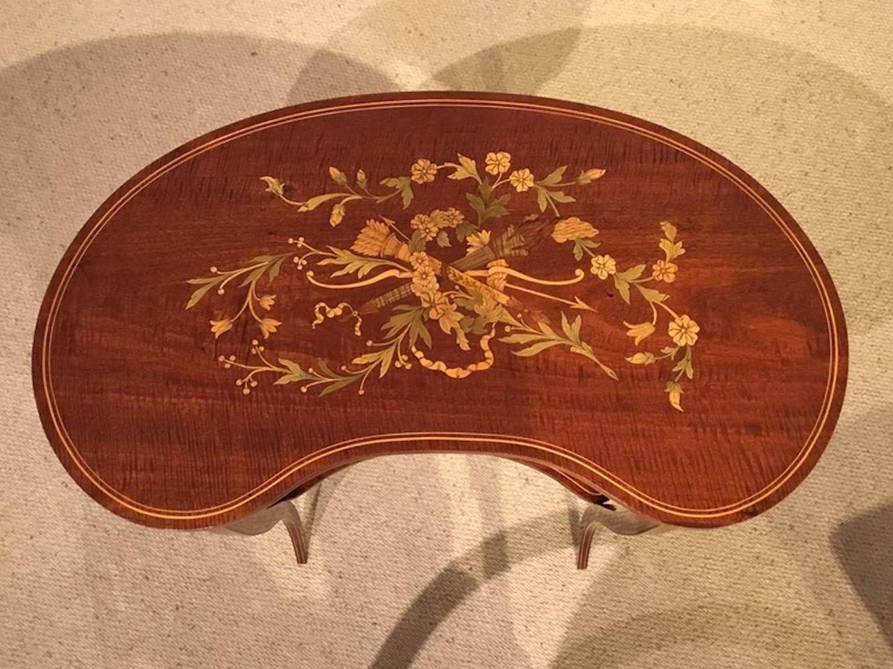 A beautiful mahogany and marquetry inlaid Edwardian Period kidney shaped occasional table. The kidney shaped fiddleback mahogany top with a wonderful marquetry inlaid panel and a variety of exotic wood and veneers. Standing on shaped supports united