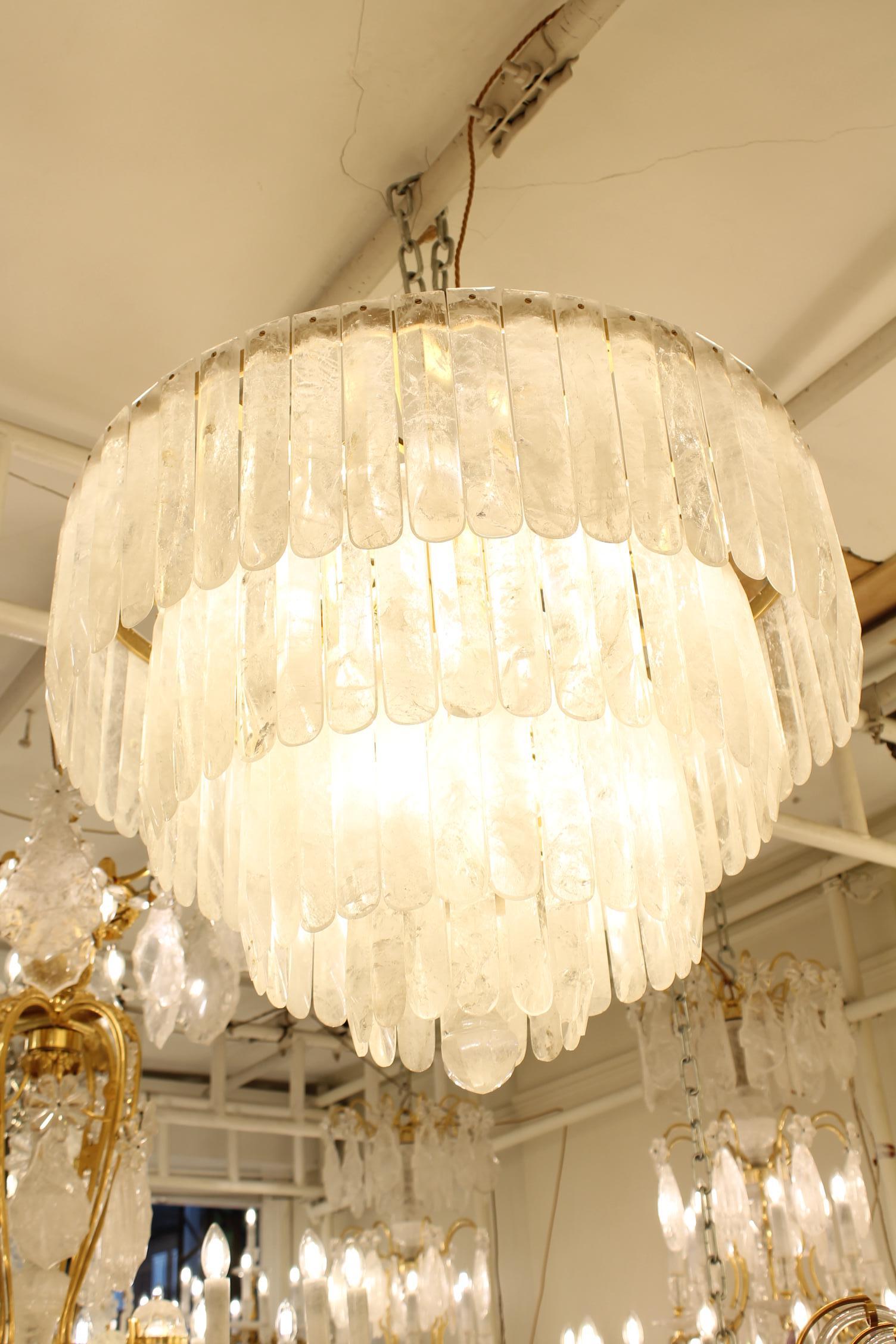 Un bellissimo  lampadario in cristallo di rocca composto da 4 piani di riduzione circolari in bronzo, ognuno dei quali è abbondantemente appeso con un totale di 135 gocce di cristallo di rocca intagliate a mano. Una bellissima goccia di cristallo di