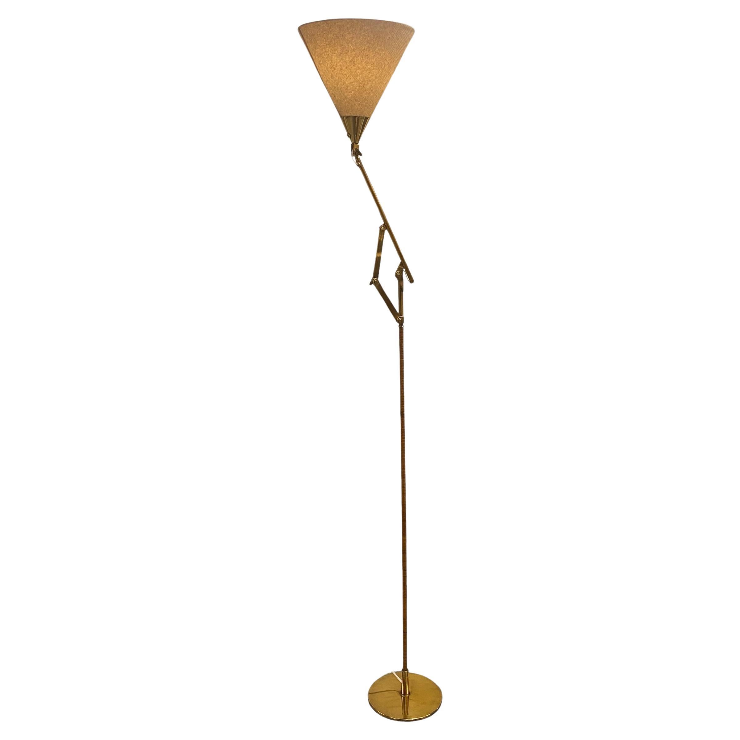 A brass floor lamp model 9605 designed by Paavo Tynell and manufactured by Taito Oy in Finland in the 1950s. This is one of the rarest Paavo Tynell floor lamps, for it is not seen often. Featuring the usual rattan stem, and an adjustable mechanism