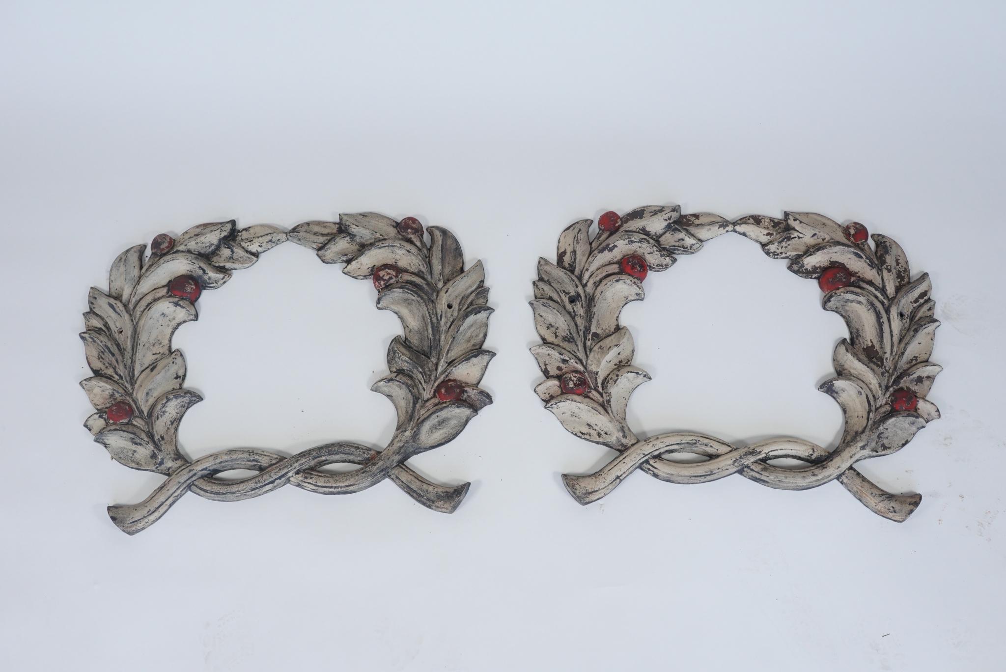 Dating from the early 20th century, this pair of cast iron wreaths have their original paint preserved. They would have been mounted on a building or monument for decoration.