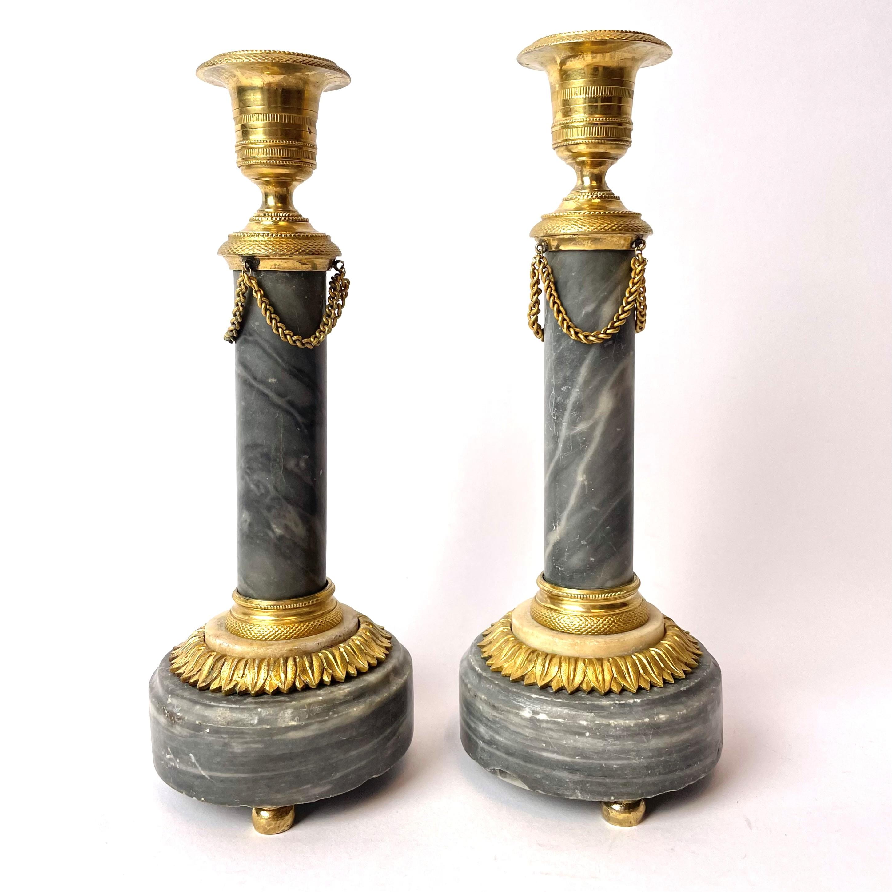 A beautiful pair of French candlesticks in Louis XVI, circa 1780. The candlesticks are made of Bleu Turquin marble with beautifully patinated details of gilded bronze.

Wear consistent with age and use.