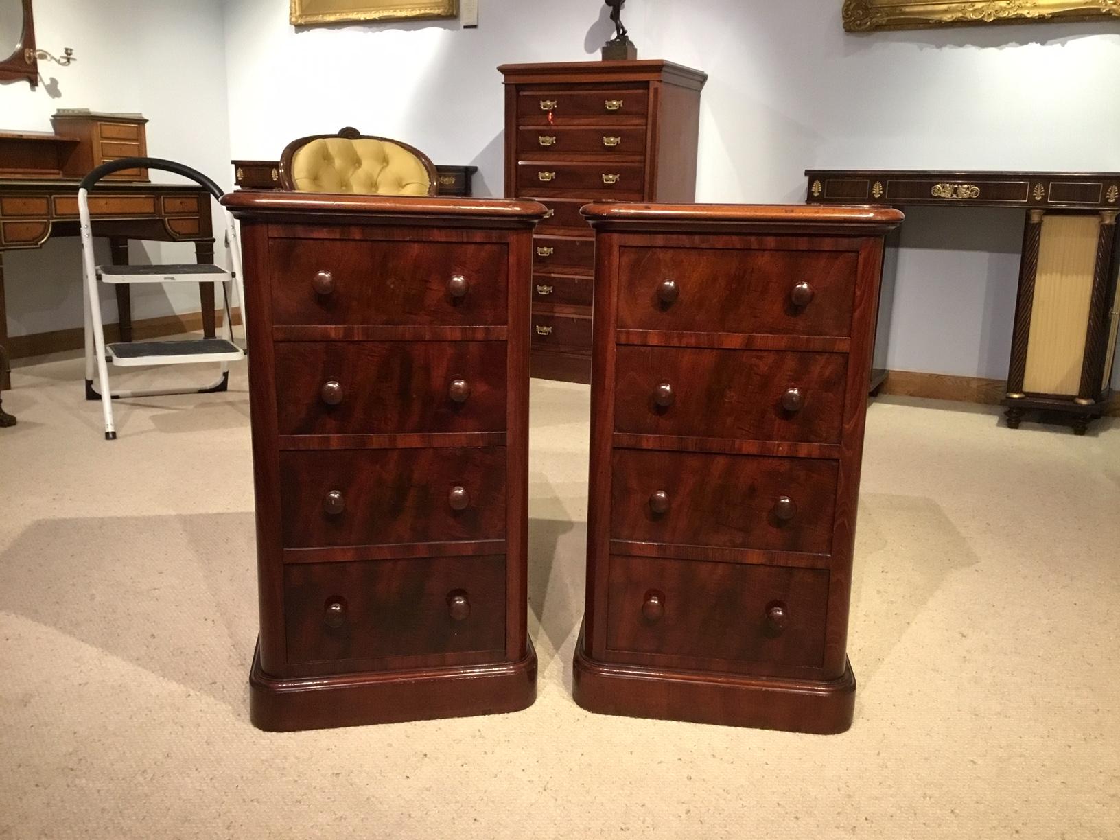 A beautiful pair of mahogany Victorian Period bedside chests. Each with a solid mahogany rounded top above an arrangement of four graduated mahogany lined drawers with beautiful flame veneered fronts, rounded corners and the original mahogany drawer